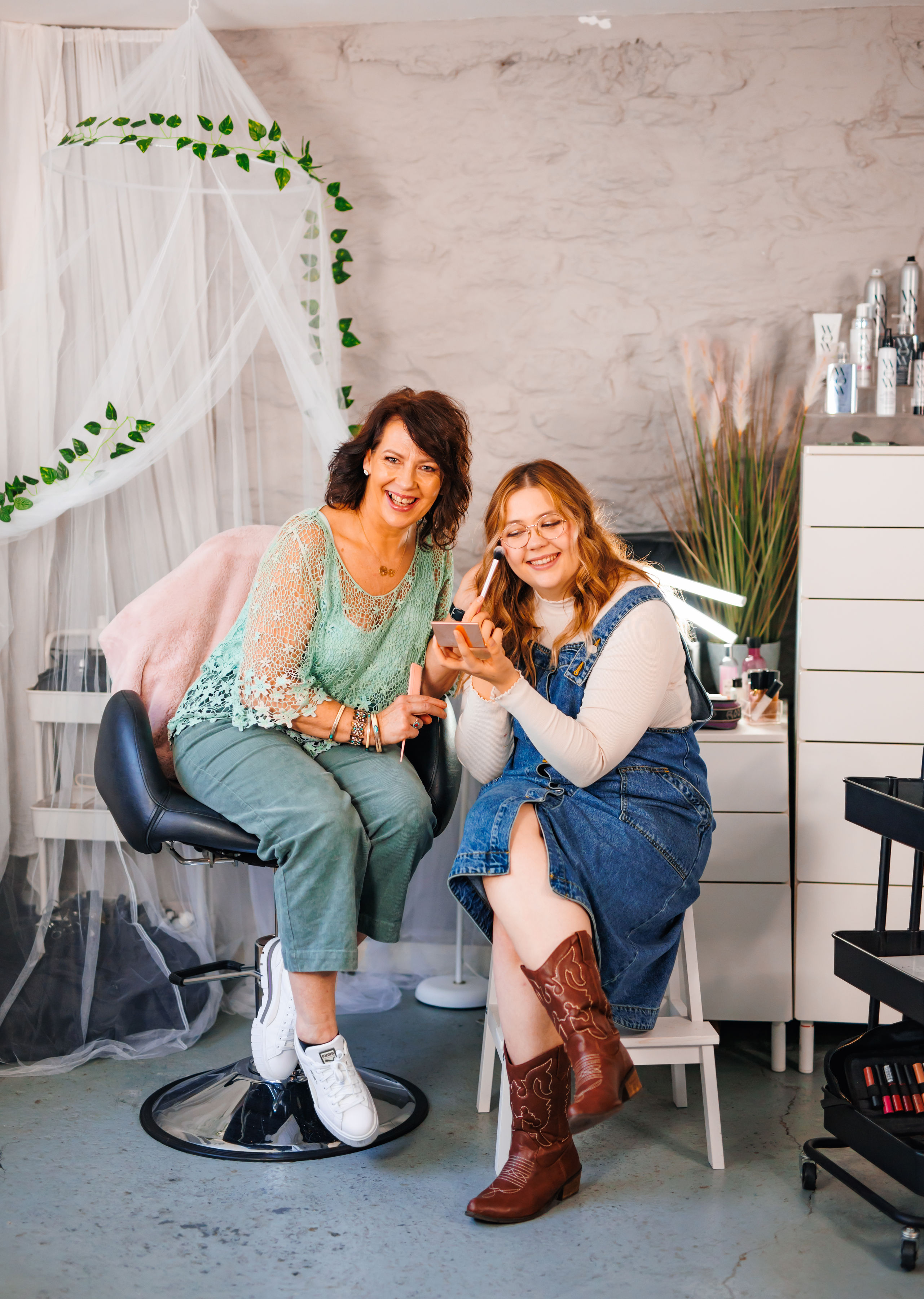 A mother and daughter hair and make up team sat smiling together in their studio