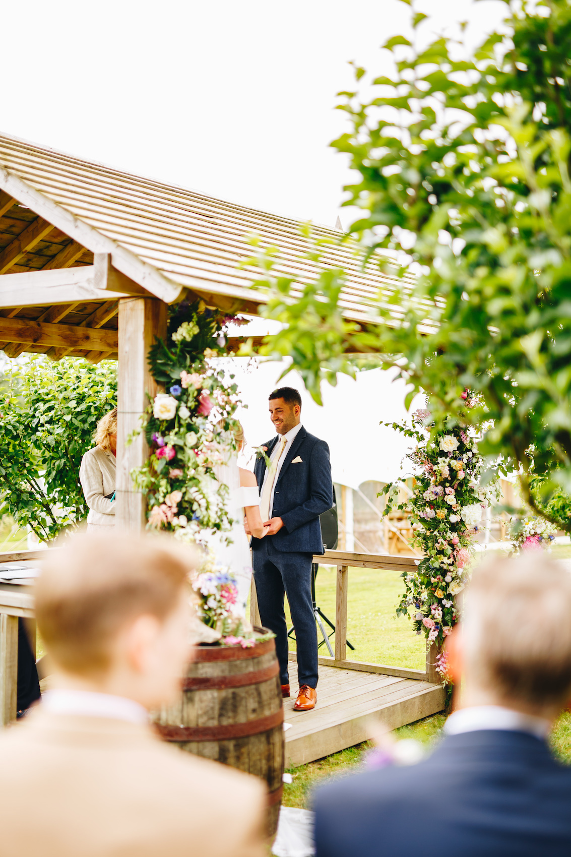 Bride and groom during their wedding ceremony under a wooden pergola adorned with flowers