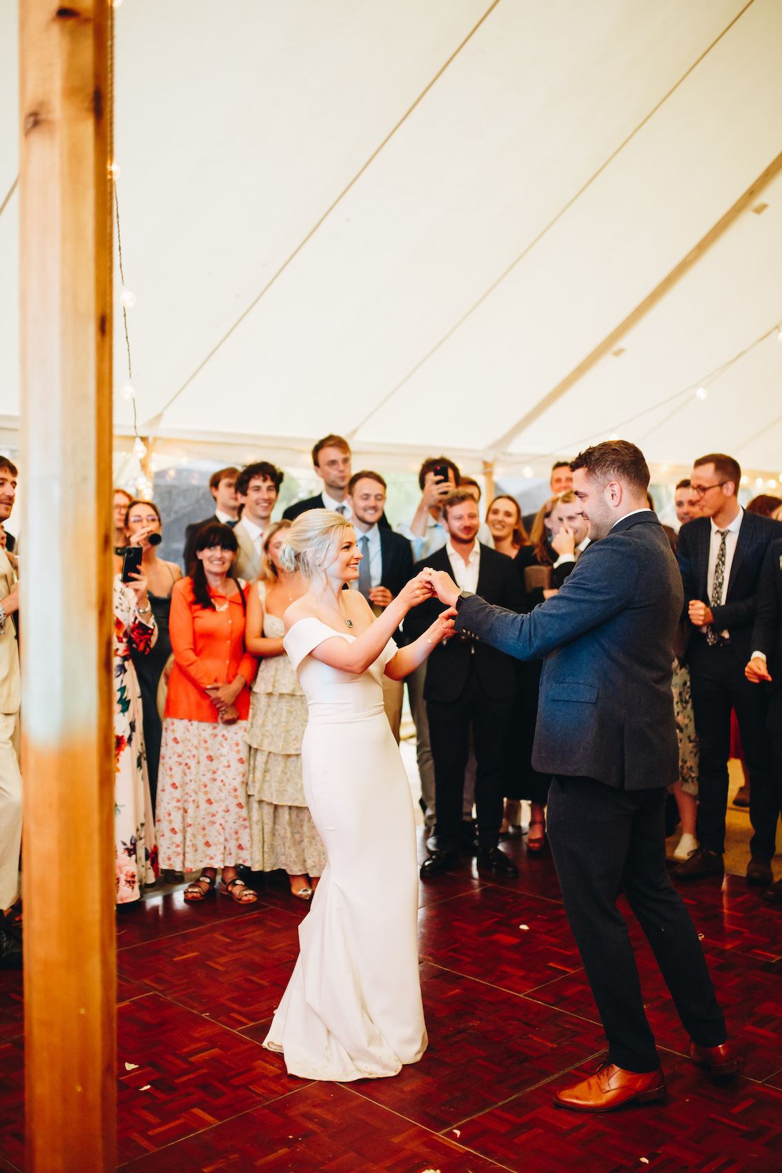 First dance joy, the bride and groom on the marquee's dancefloor as their friends and family look on