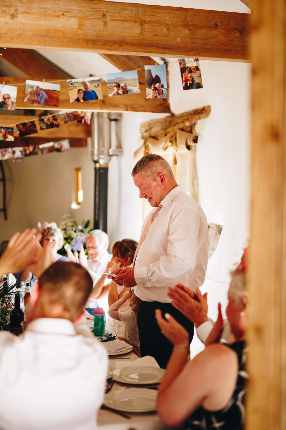 Groom stands to give his speech, with clapping guests around him