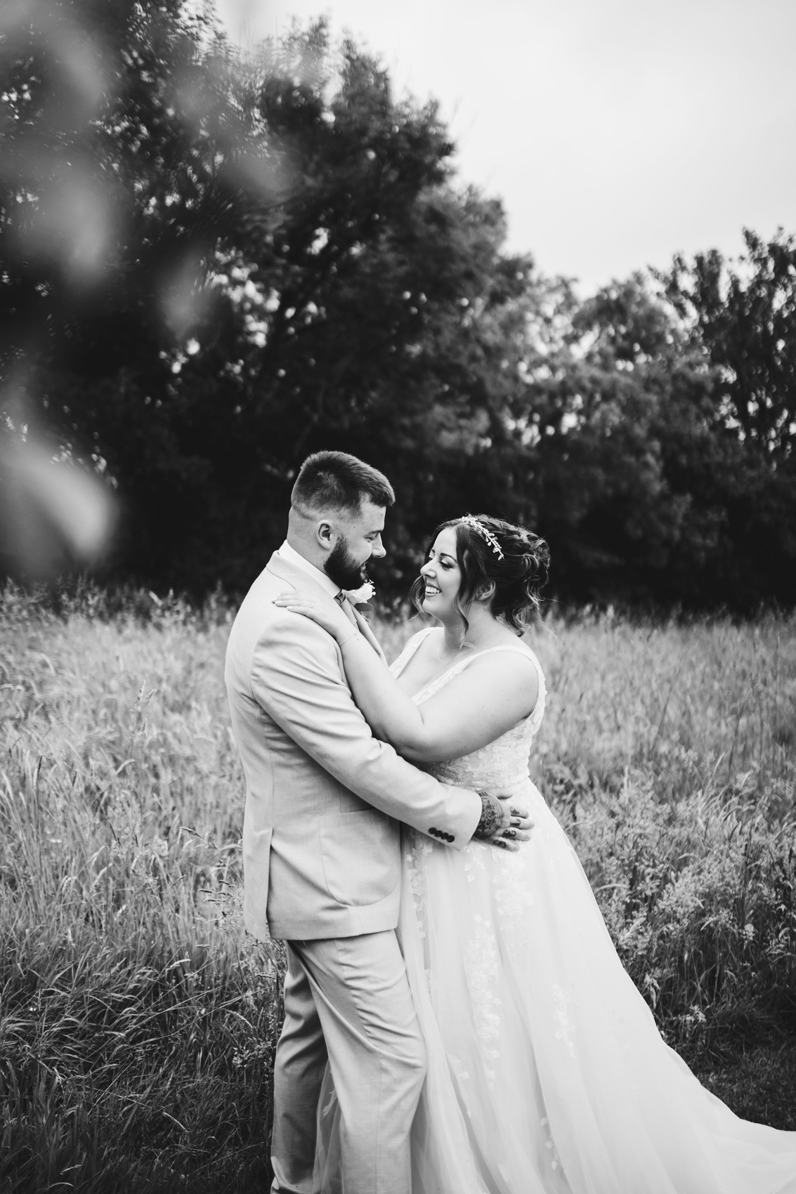 Black and white photo of bride and groom, holding each other in a field