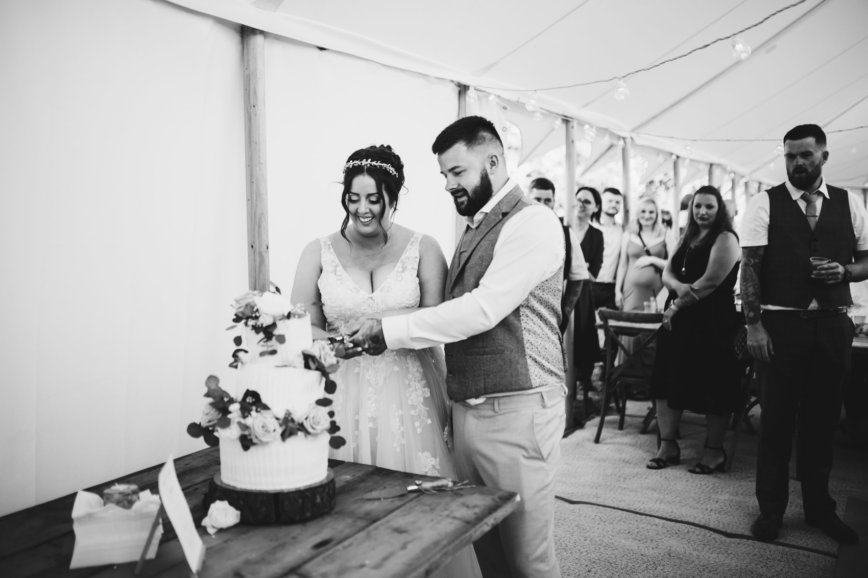 Black and white photo of newlyweds cutting their wedding cake