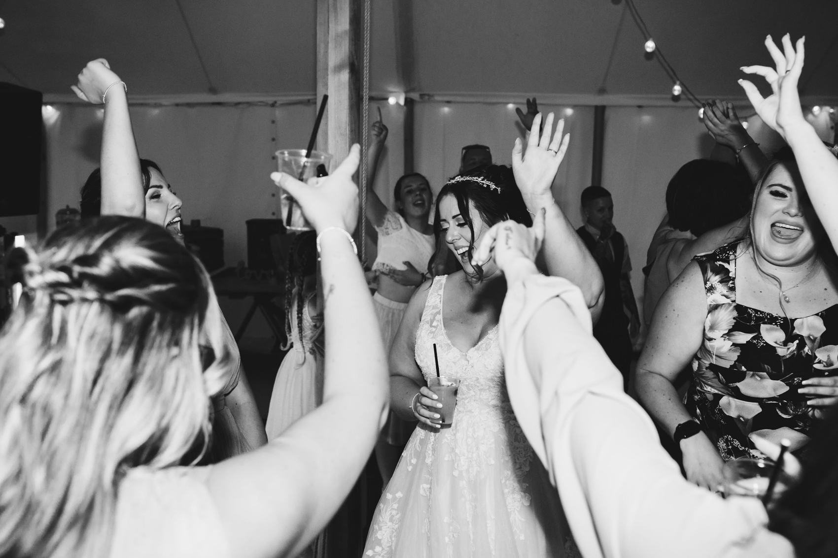 Black and white photo of bride and guests partying with their arms in the air