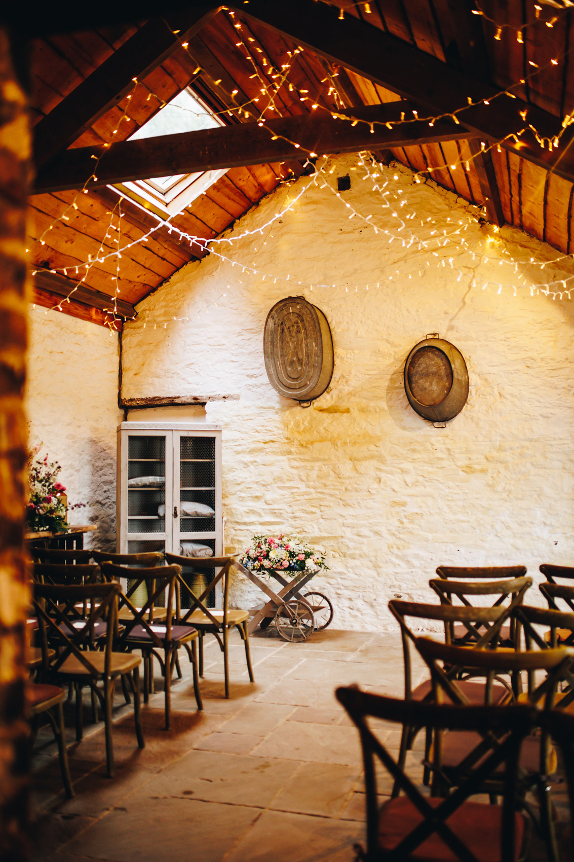 Ceremony area all set up with wooden chairs and florals on a wooden wheelbarrow