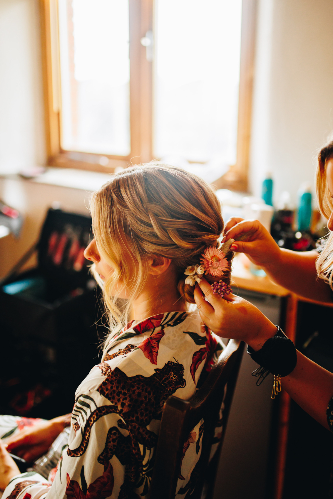 Photograph of a bride from the side getting her hair done, flowers being put into place