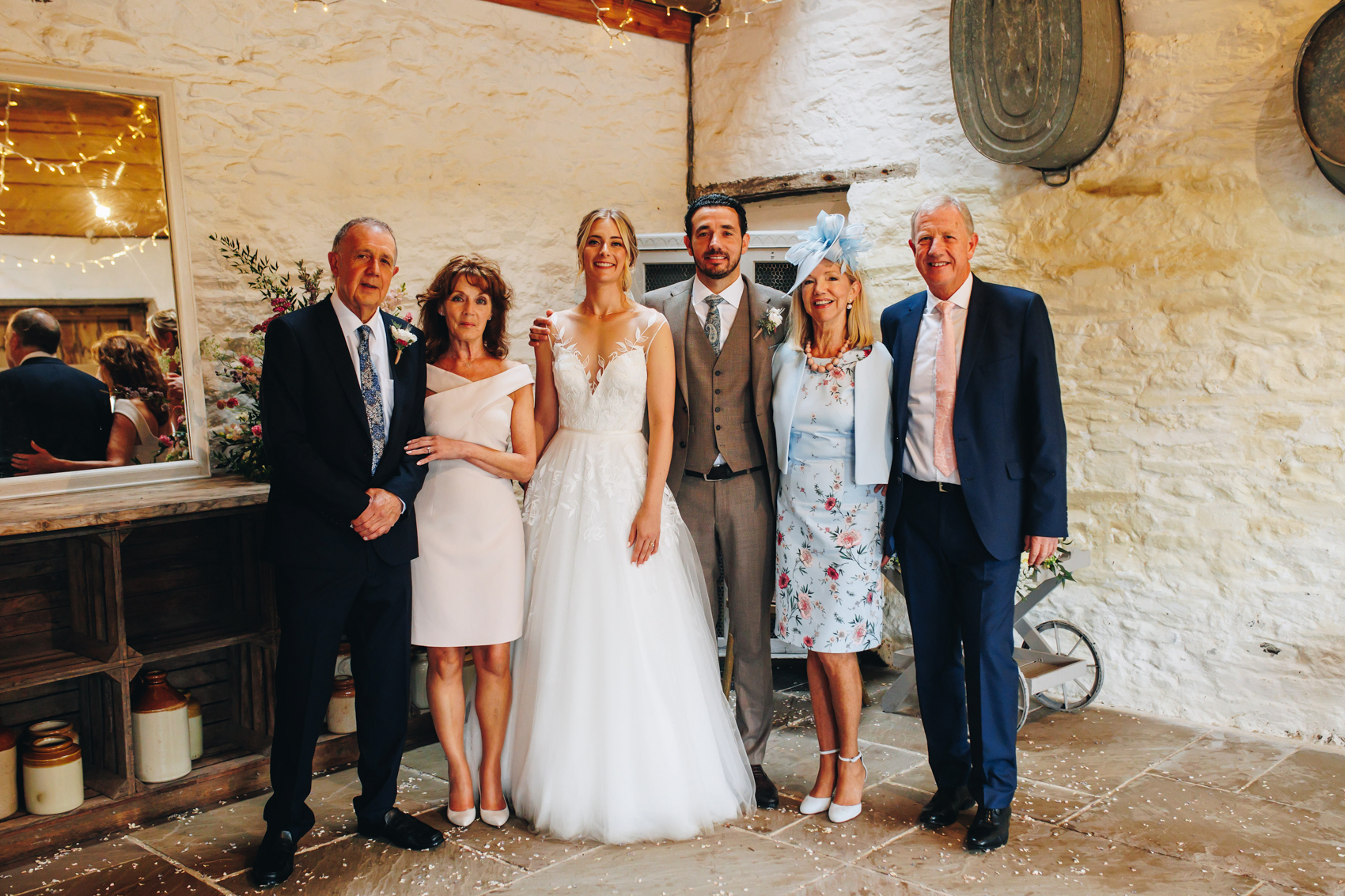A group photo of the newlyweds with both sets of parents, in a barn-like room