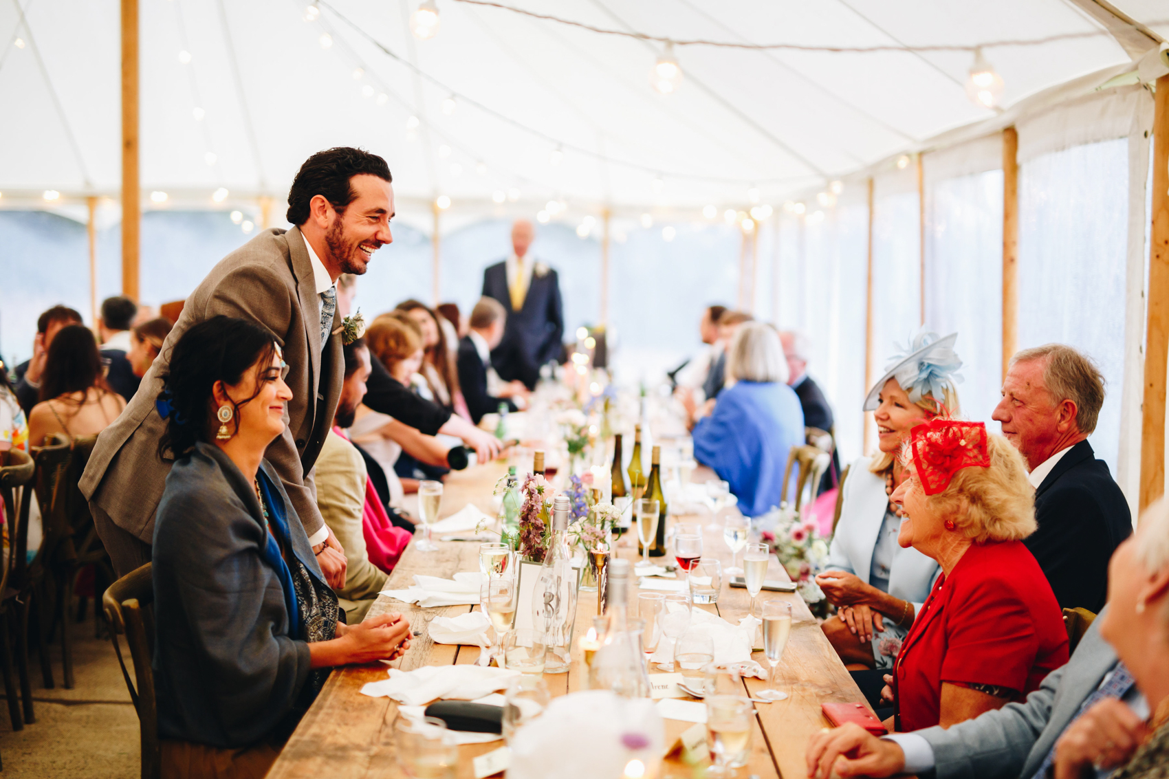 Groom circulating and chatting with guests across a table