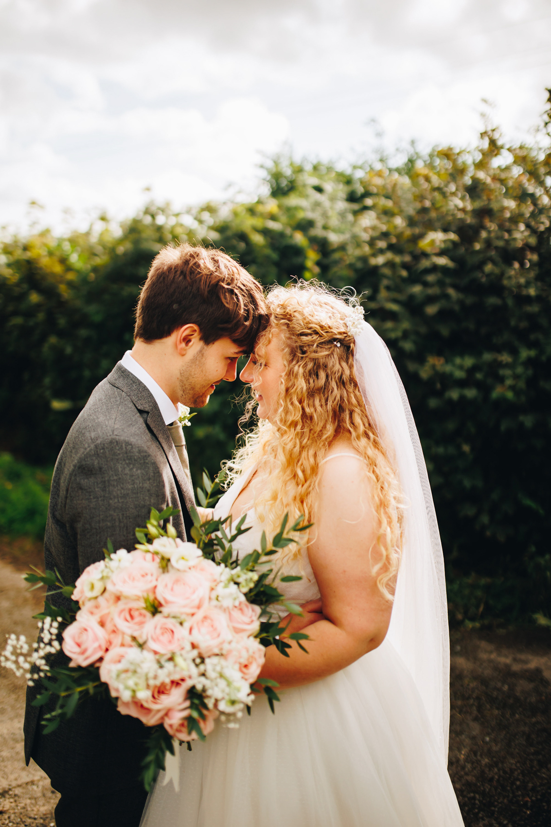 Bride and groom forehead to forehead in a country lane
