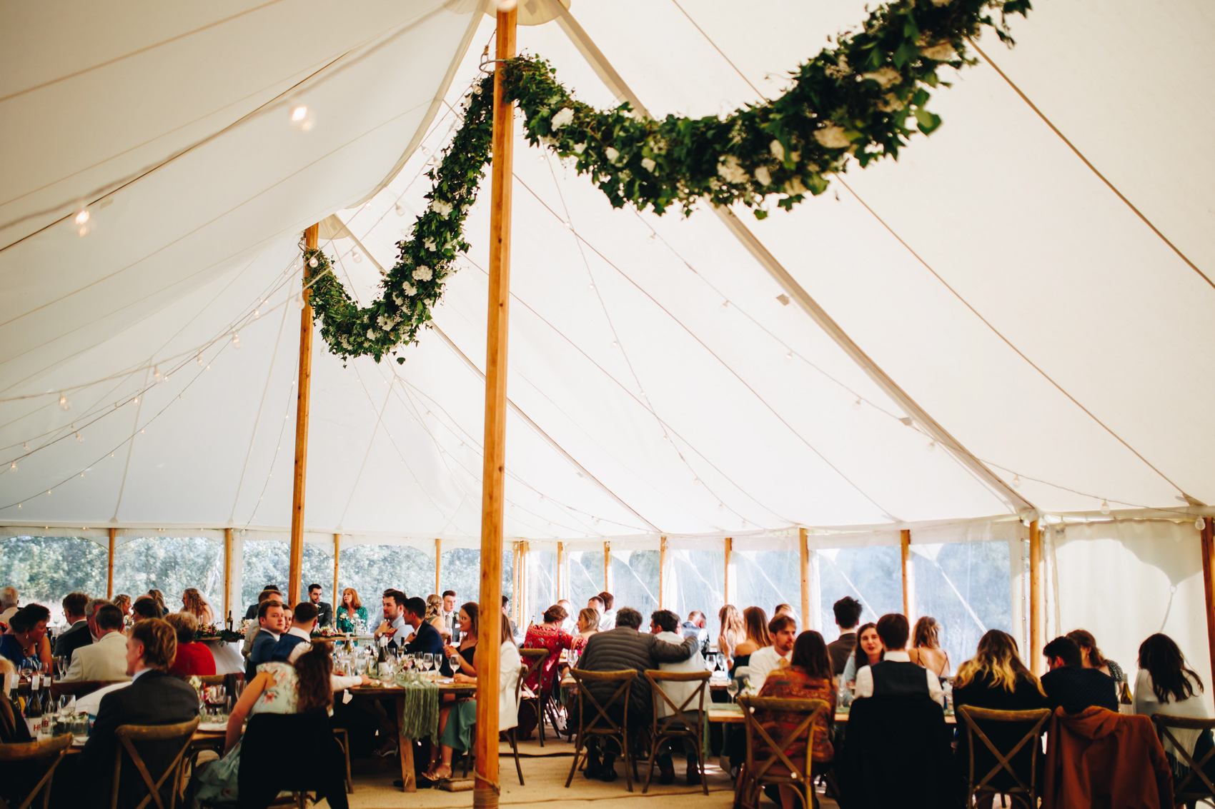 Floral garland hanging in the marquee above wedding reception guests