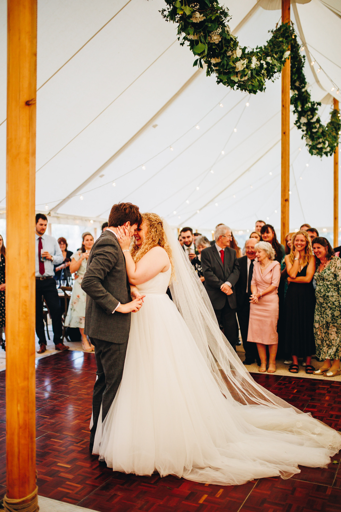 Bride and groom have their first dance on the dancefloor surrounded by their loved ones