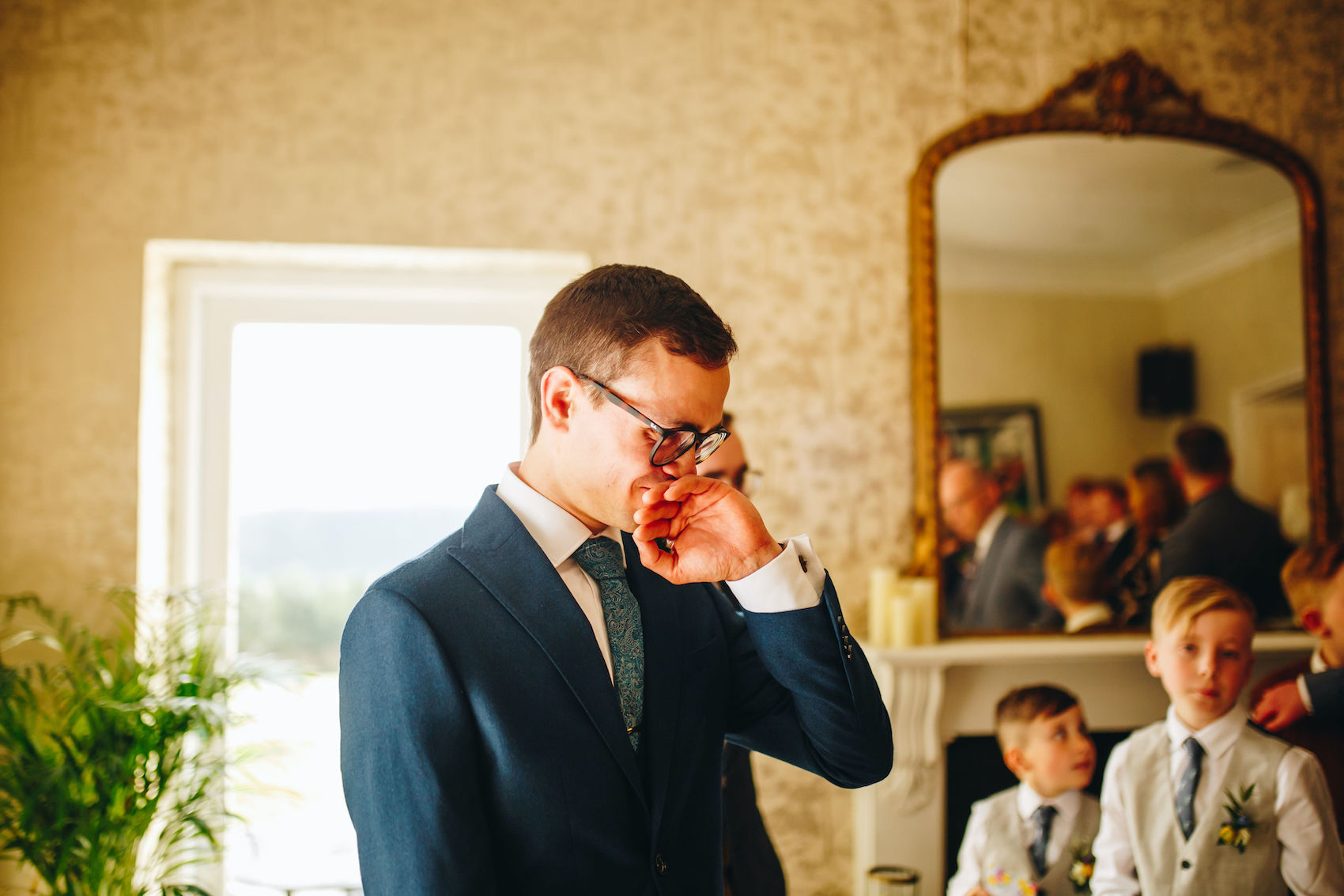 Groom with his hand to his face as he tears up at seeing his fiancée in her wedding dress for the first time