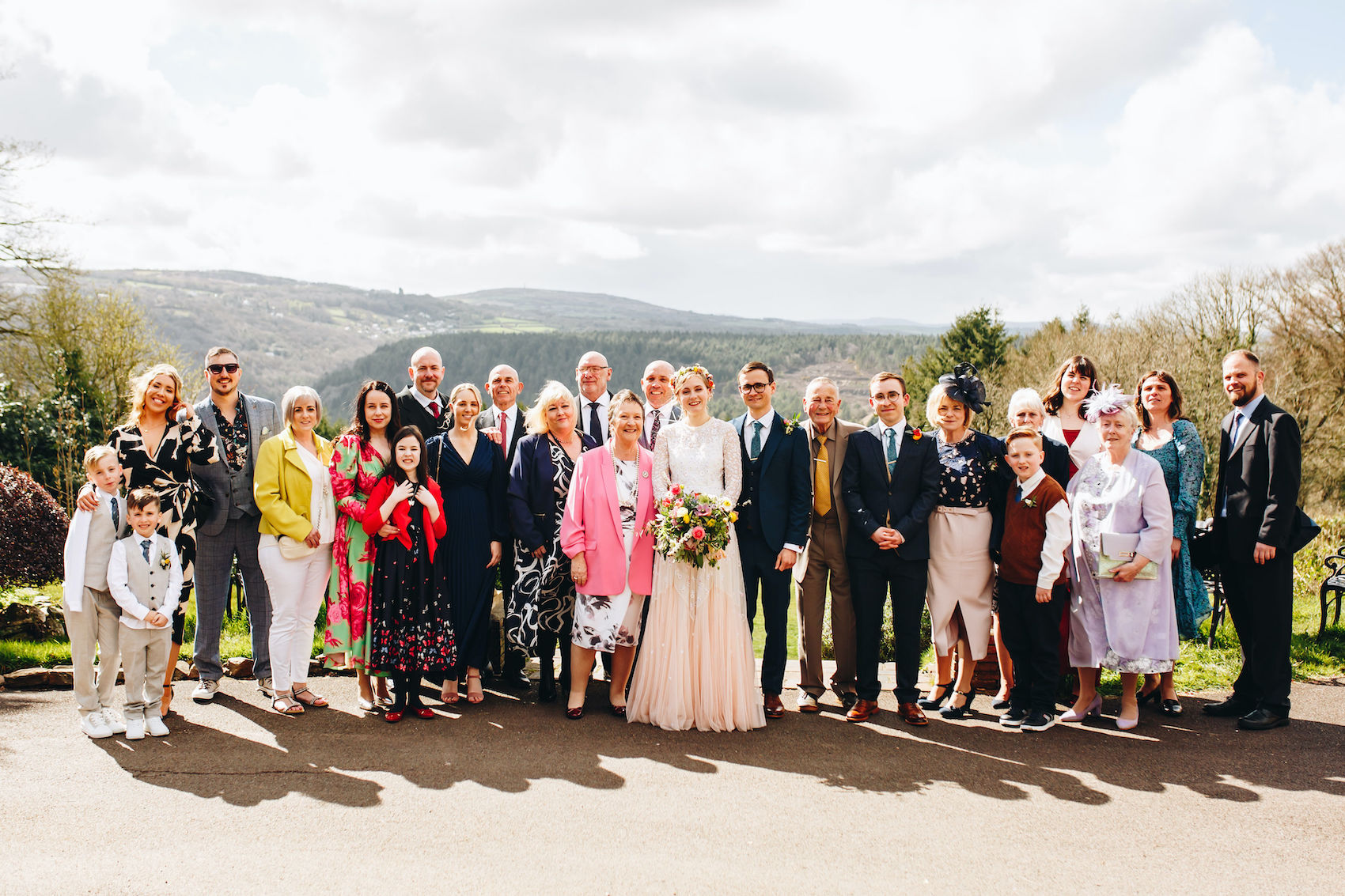 Bride and groom smile with family for a family group photo