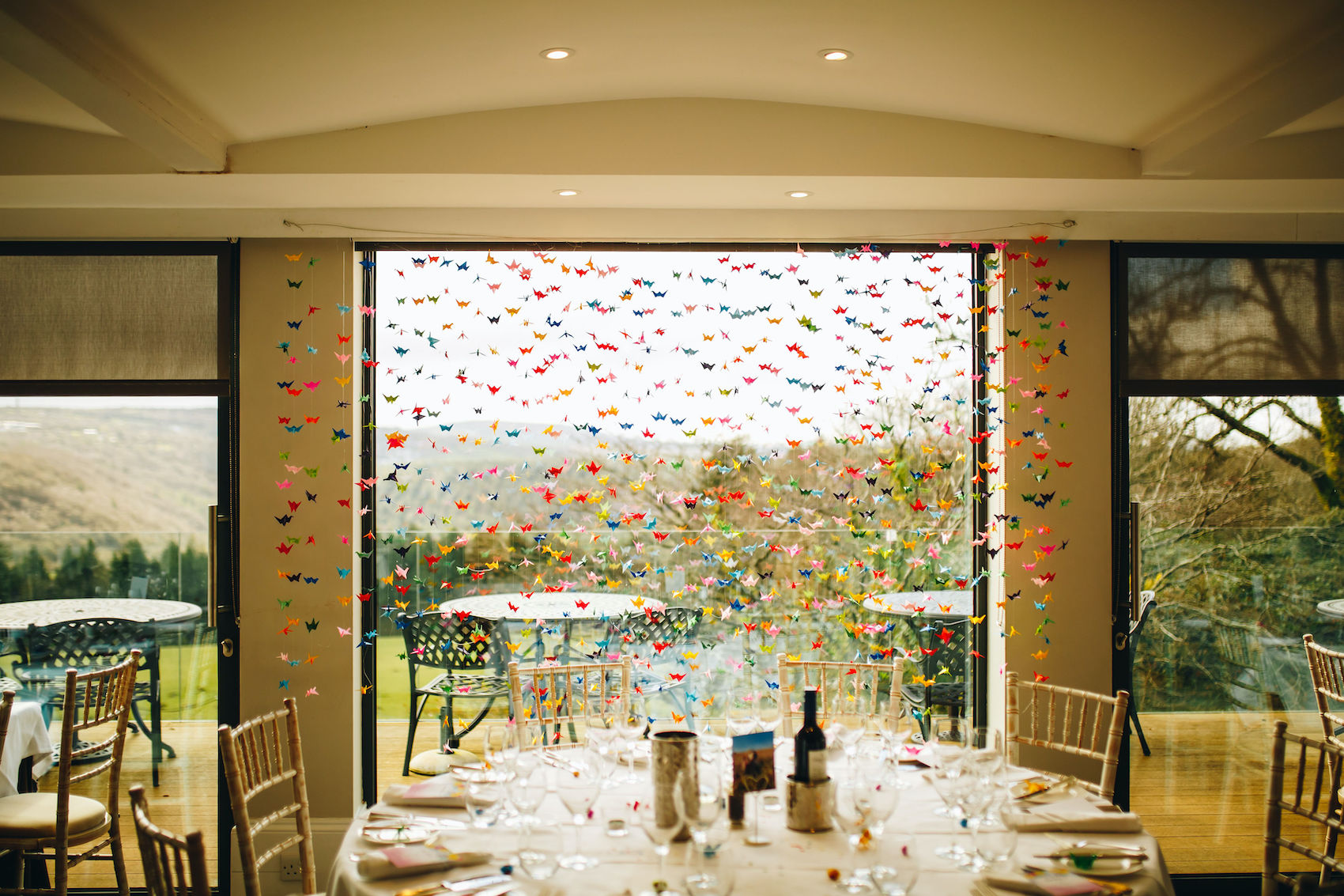 1000 paper cranes, made by the bride and groom and friends, hung in front of the window which will be behind the couple when they sit at their reception