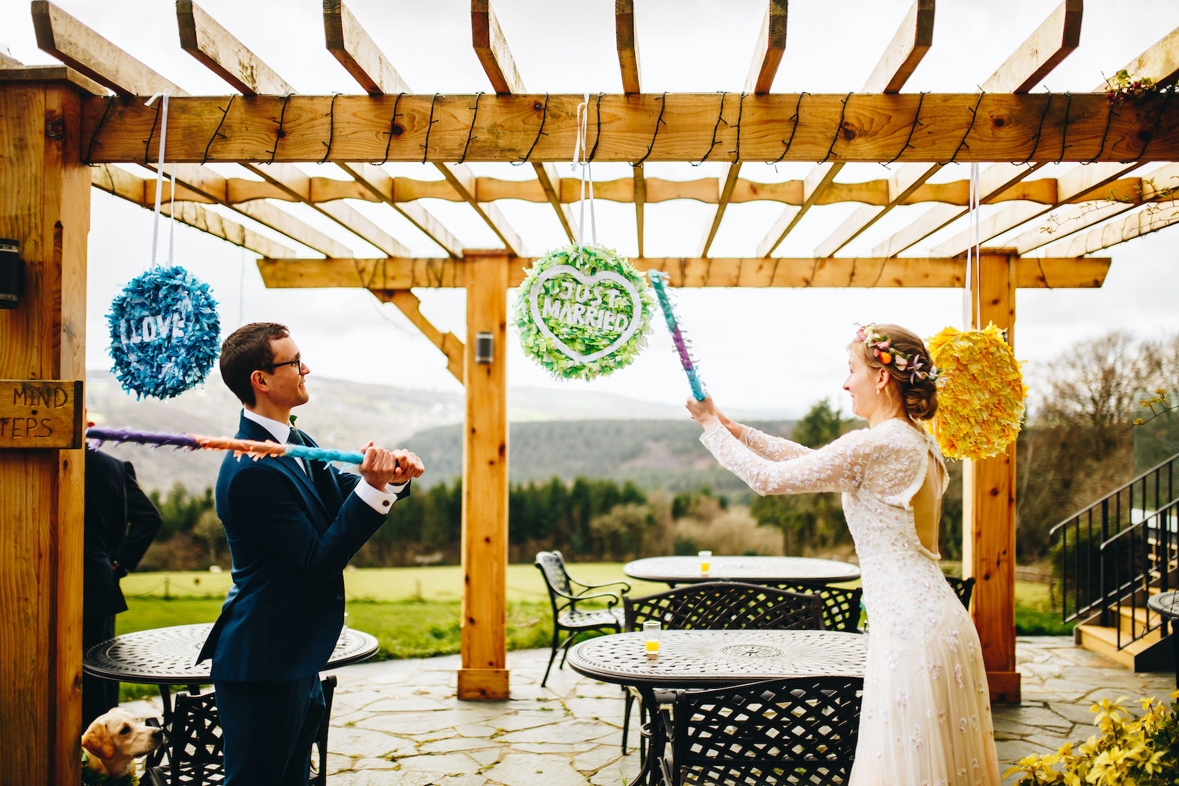 Bride and groom hit piñatas that look like Love Heart sweets that say "JUST MARRIED" and "LOVE"
