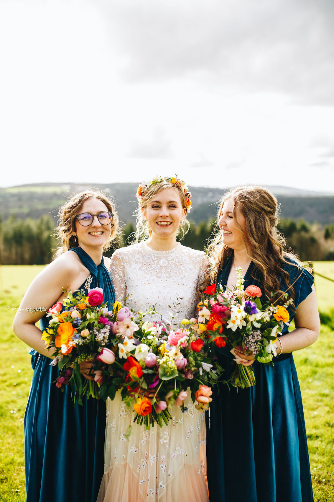 Bride and two bridesmaids all huddled in close, holding bouquets