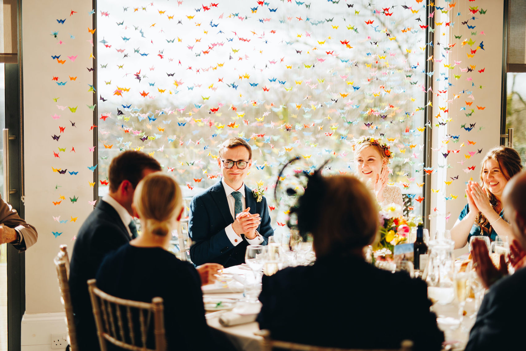 Groom tearfully claps at the best man's speech, along with his new wife and other members of the wedding