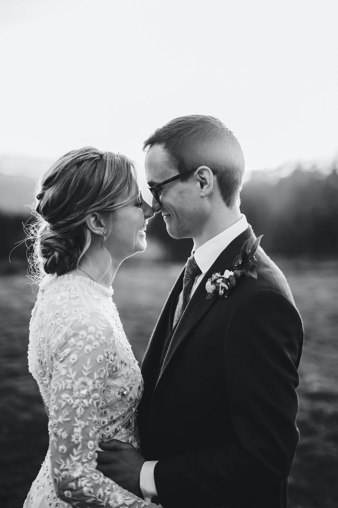 Black and white close up photo of bride and groom at sunset, with hazy light and the valley behind them