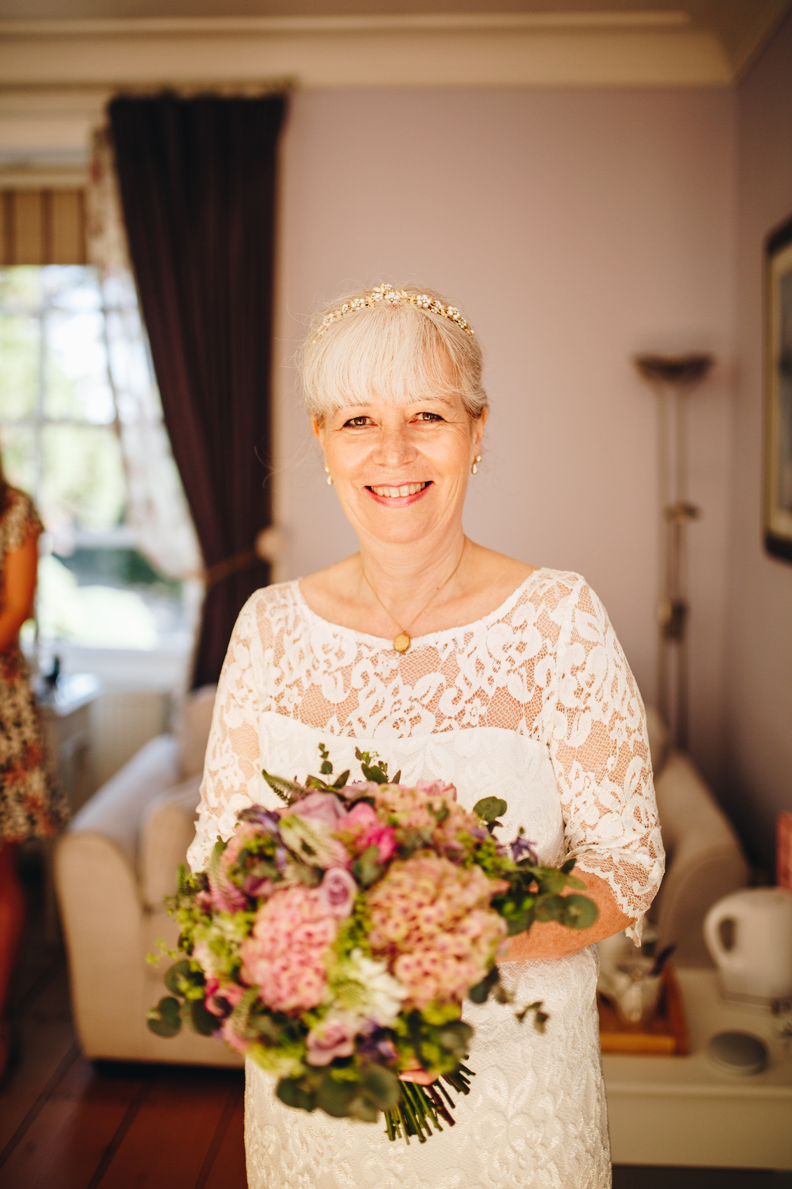 Bride smiles while holding bouquet, in a warmly lit room