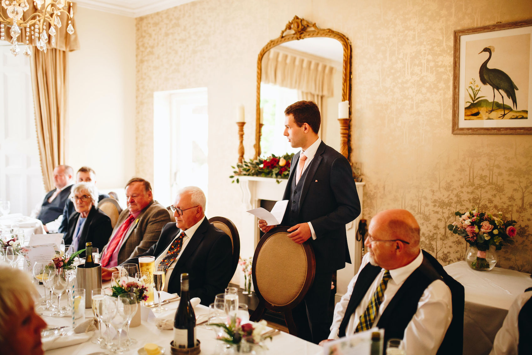 Best man stands up at the table delivering his speech in a beautiful reception room