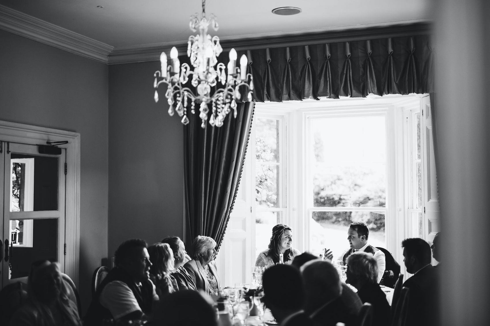 Black and white photo of bride and groom looking at each other when seated together at their reception