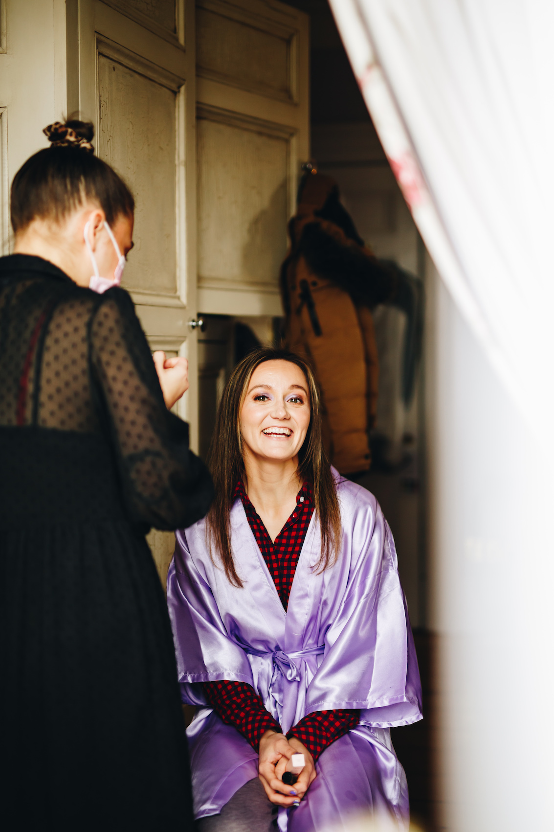 Photo of the bride having her make up done, smiling, in a lilac gown