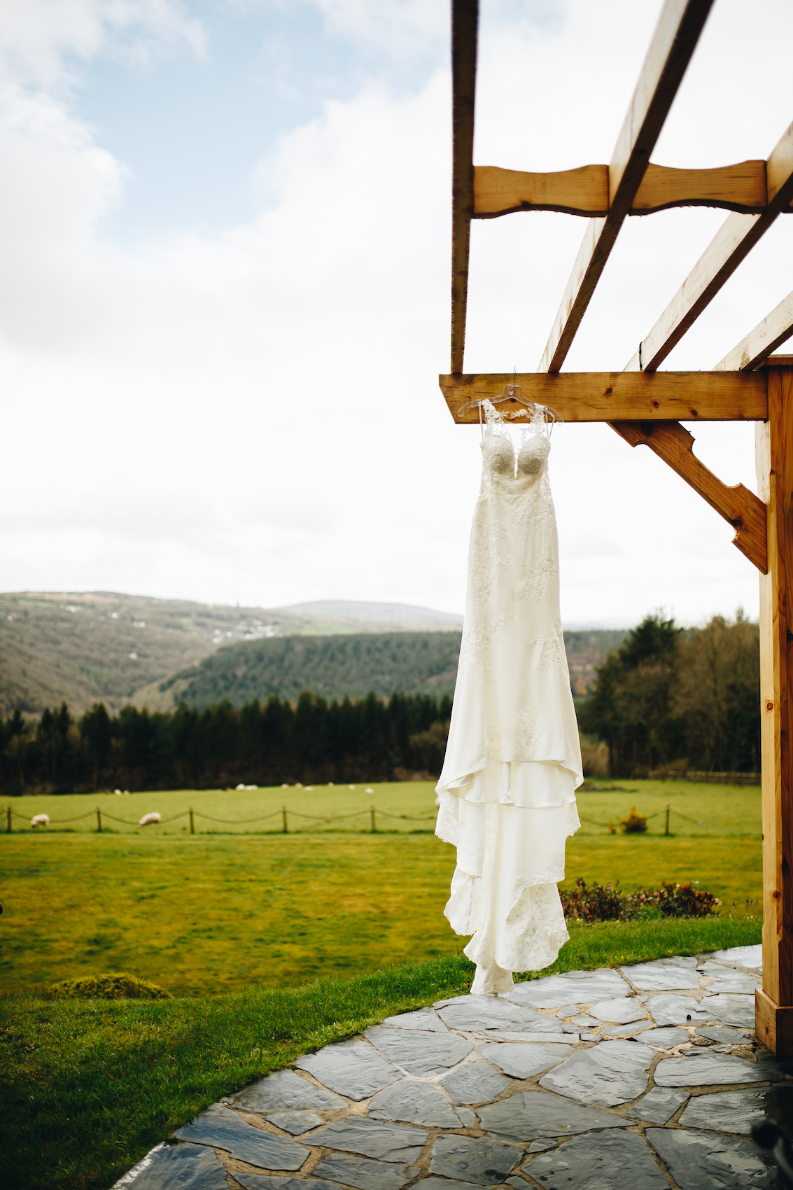 Bride's gown hanging on its hanger from the wooden veranda, with the valley in the background
