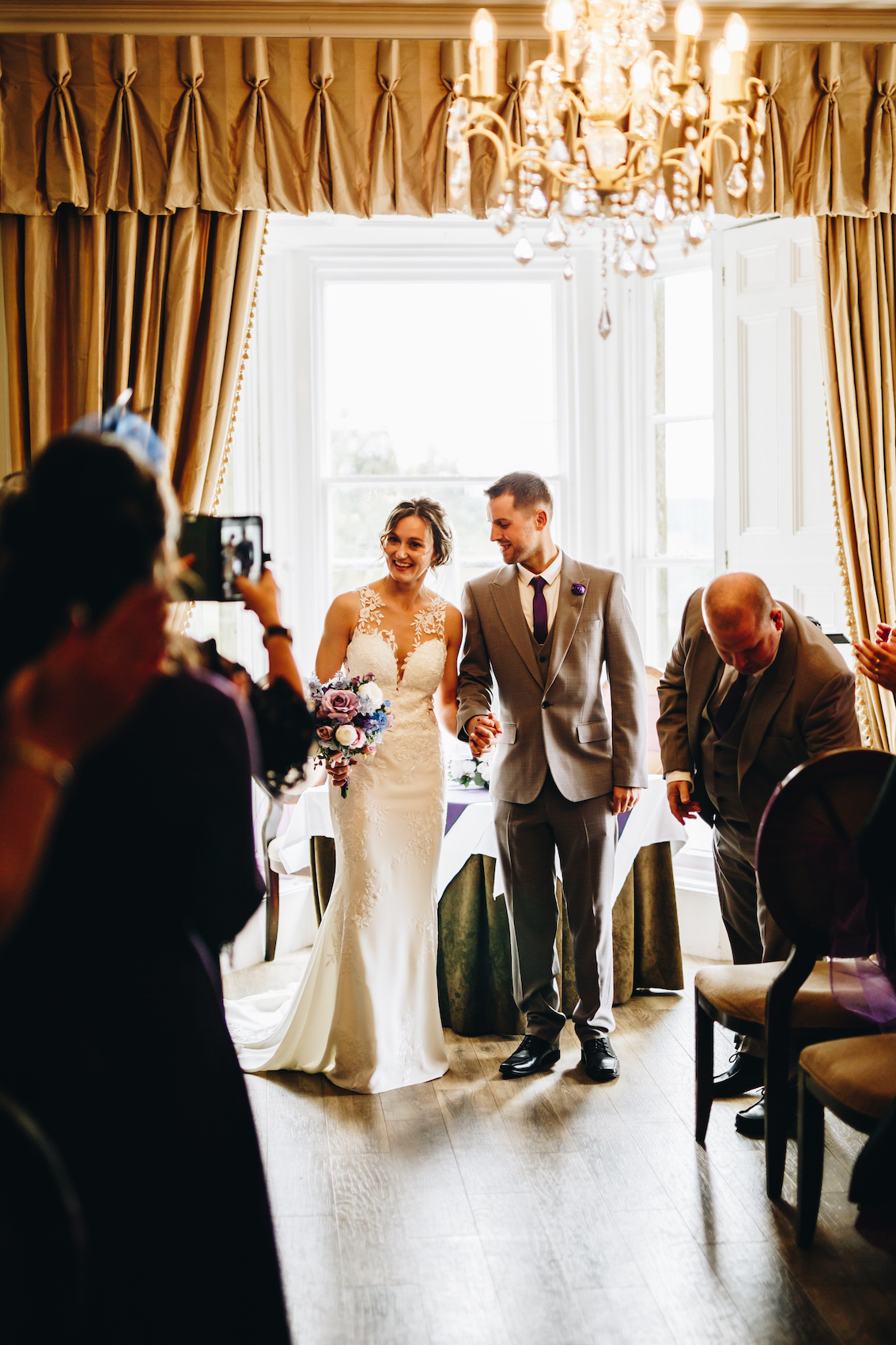 Bride and groom walking up the aisle as guests take photos.