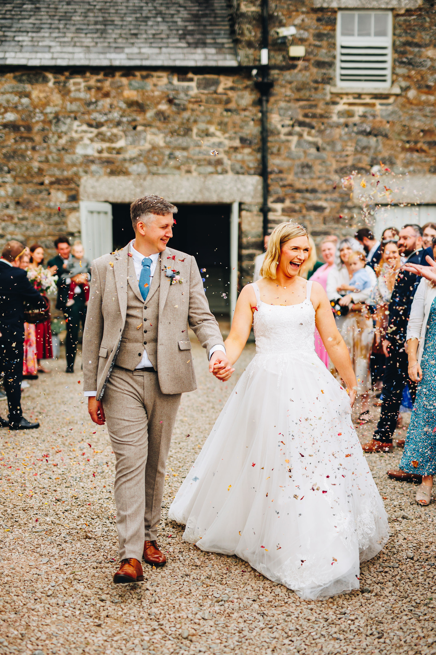 Bride and groom during confetti toss in front of barn