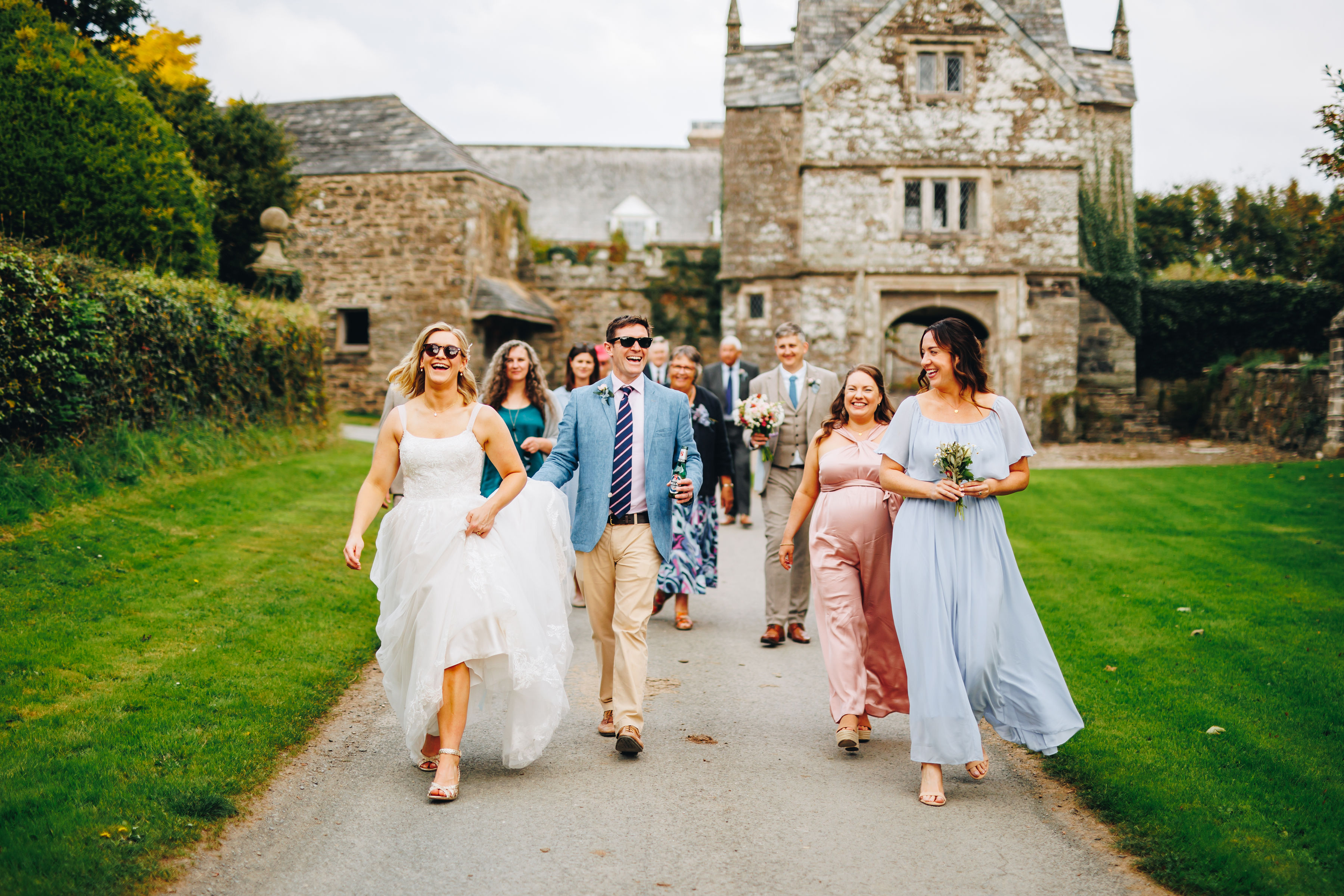 Bride and bridal party walk along lane smiling