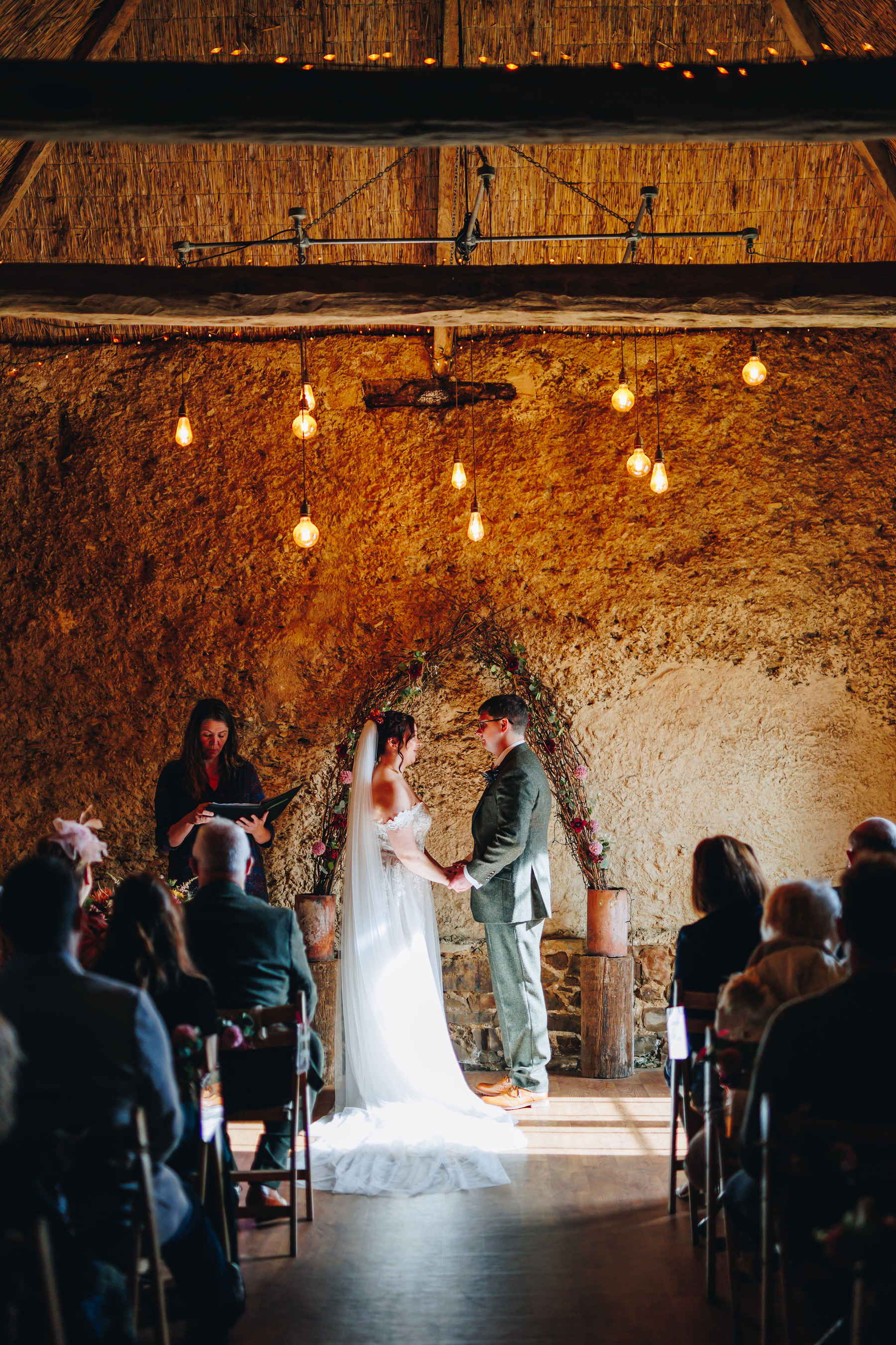 Bride and groom at the alter, in sunlight, under hanging lights