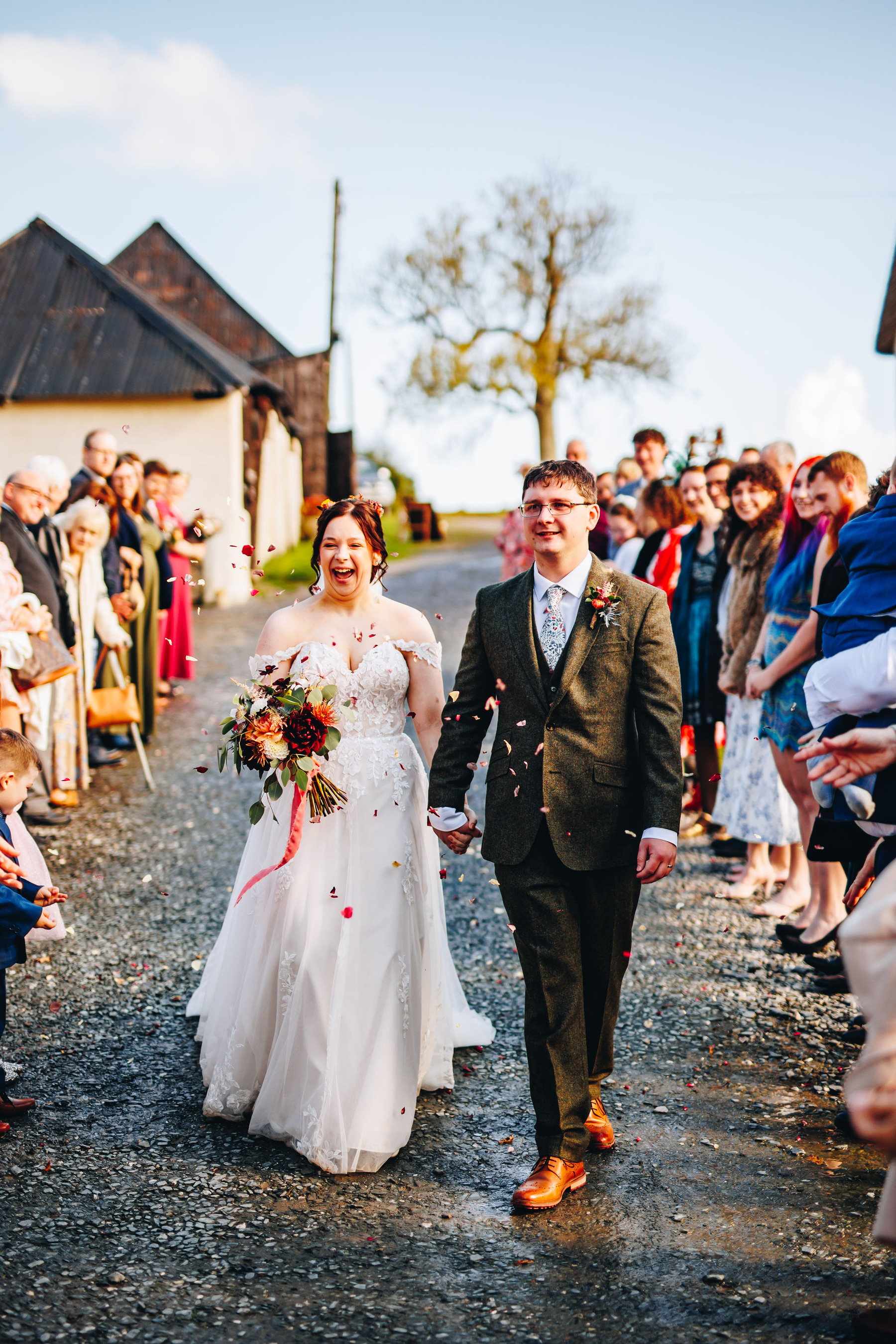 Bride and groom having confetti thrown at them at a rustic wedding venue