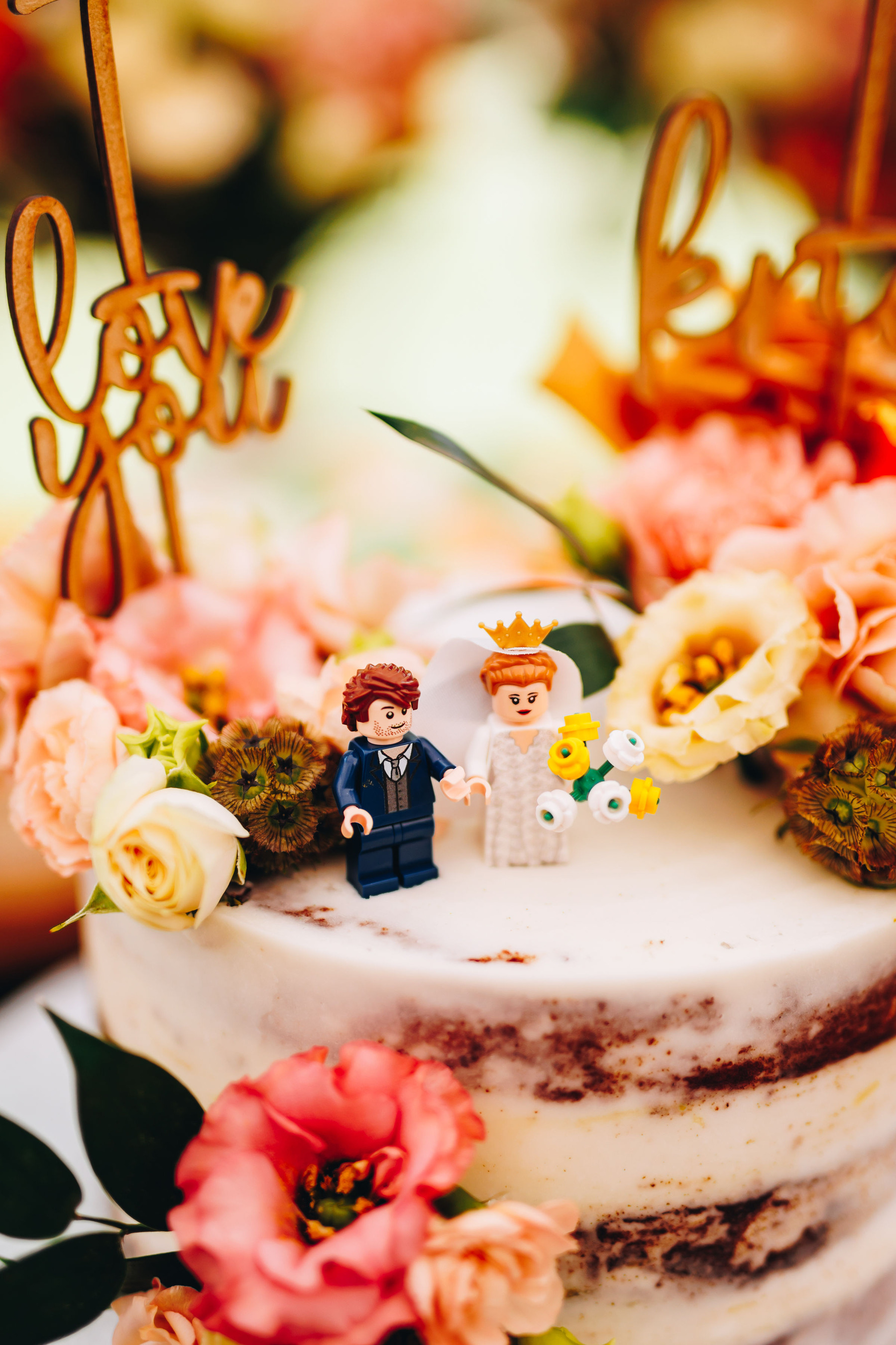 Close up of lego bride and groom on a wedding cake with florals around