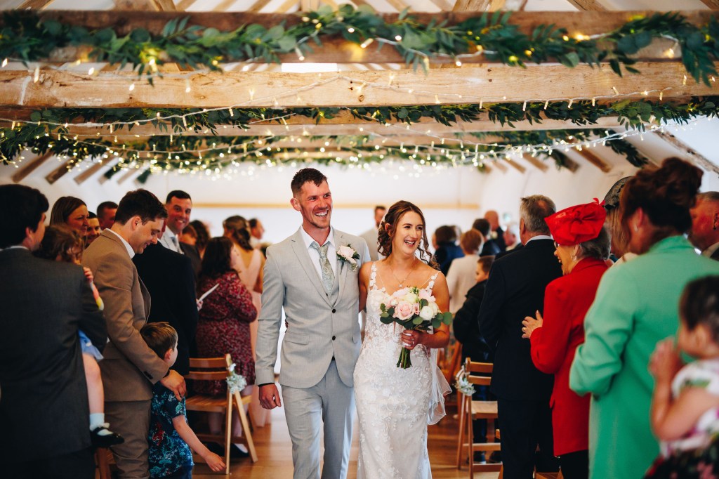 Couple smiling walking arm in arm up the aisle after getting married
