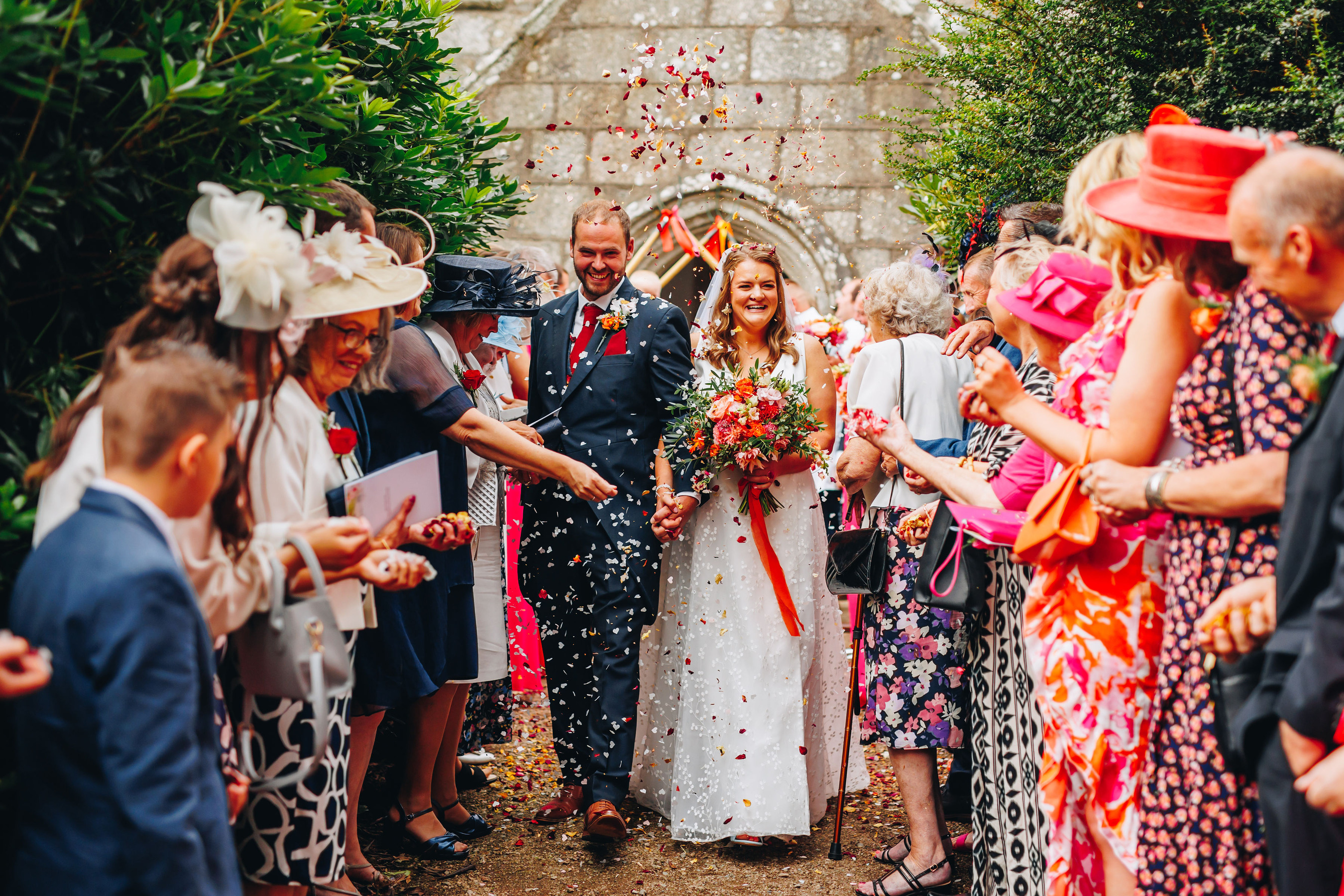 Couple walk down church path covered in pink and orange confetti