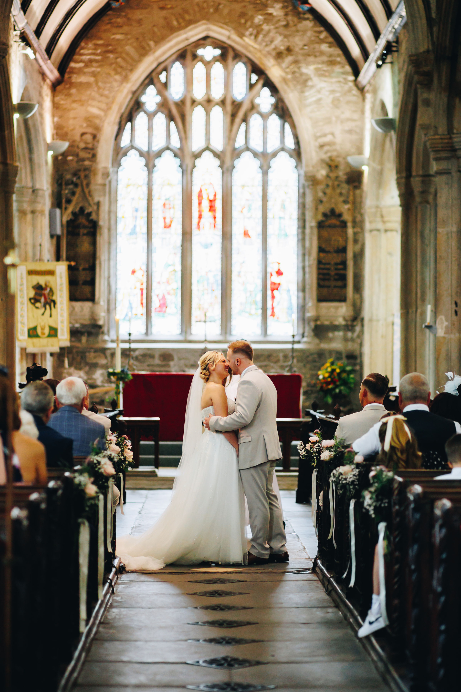 Bride and groom at the top of an aisle having their first kiss