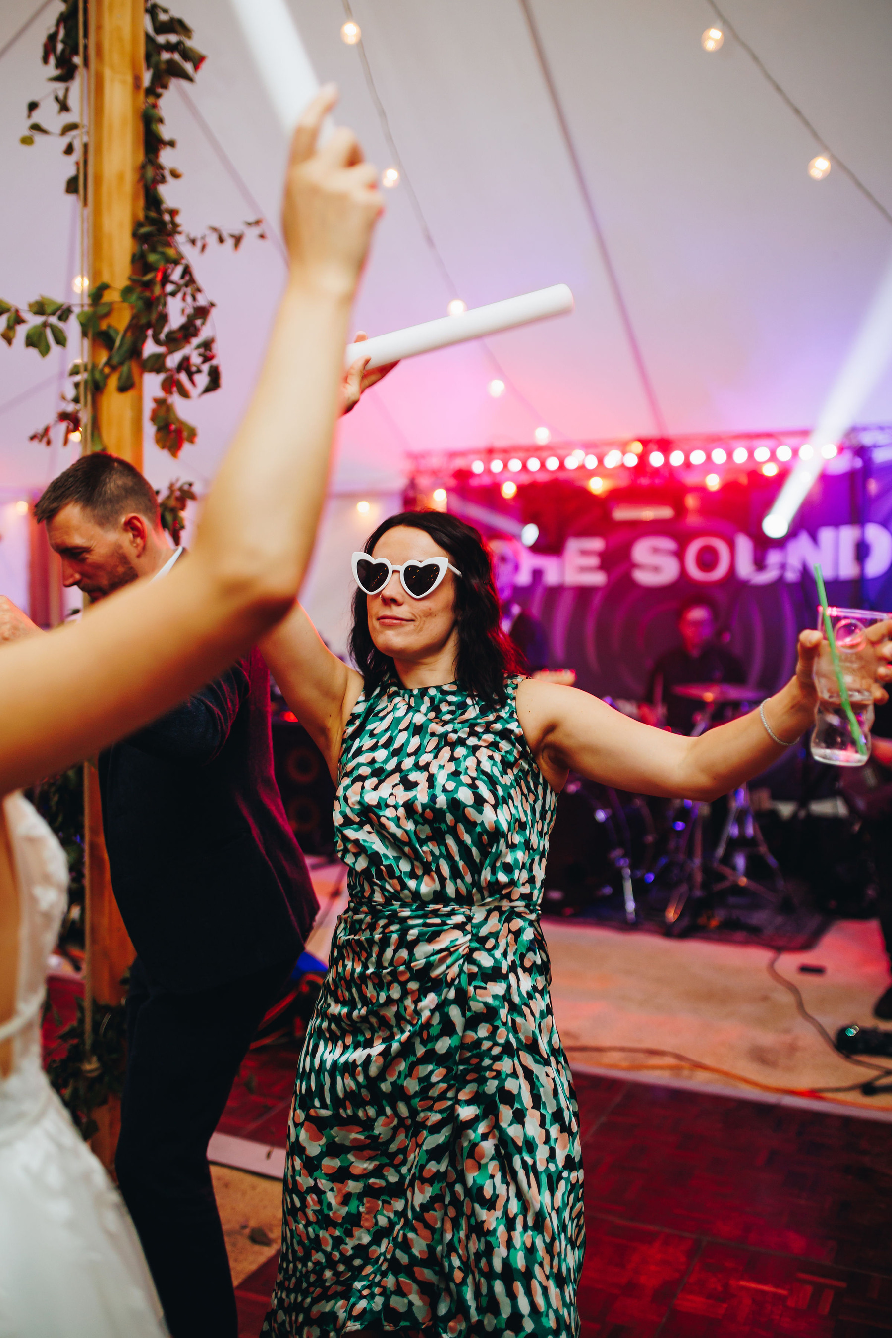Wedding guest dances with heart shaped sunglasses on