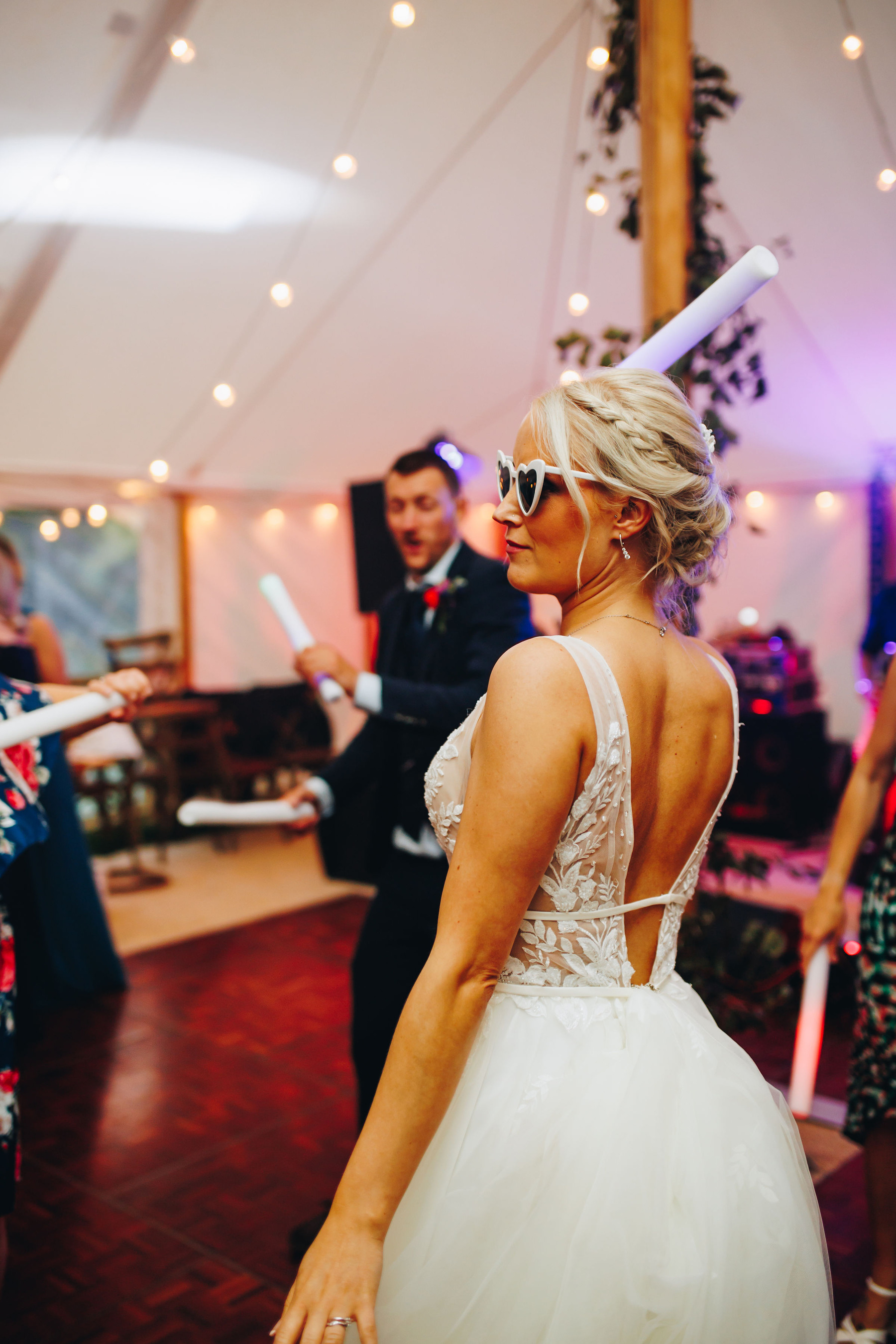 Bride dances in heart shaped sunglasses at her wedding reception