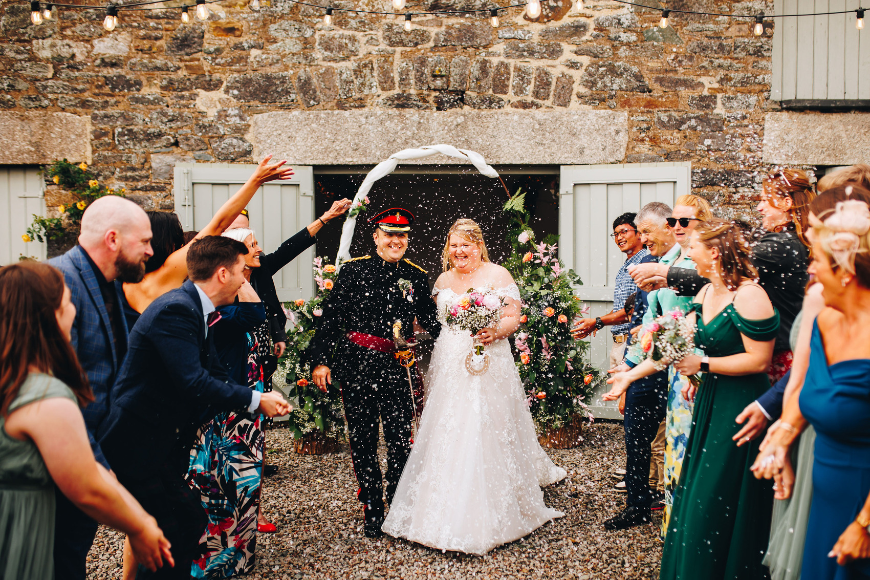 Wedding couple with confetti being thrown at them. Groom is in military suit.