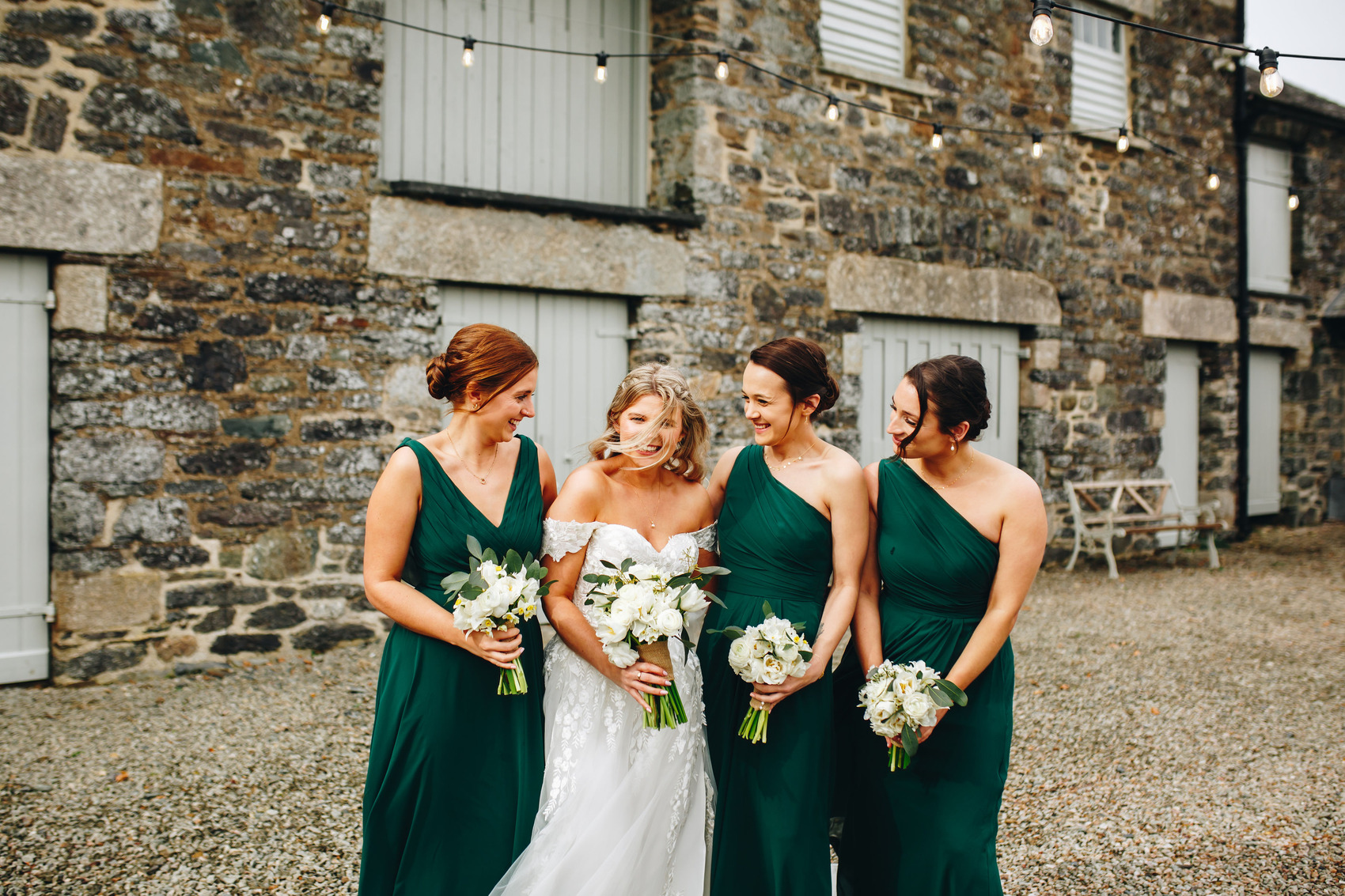 Bride and 3 bridesmaids smiling in the breeze