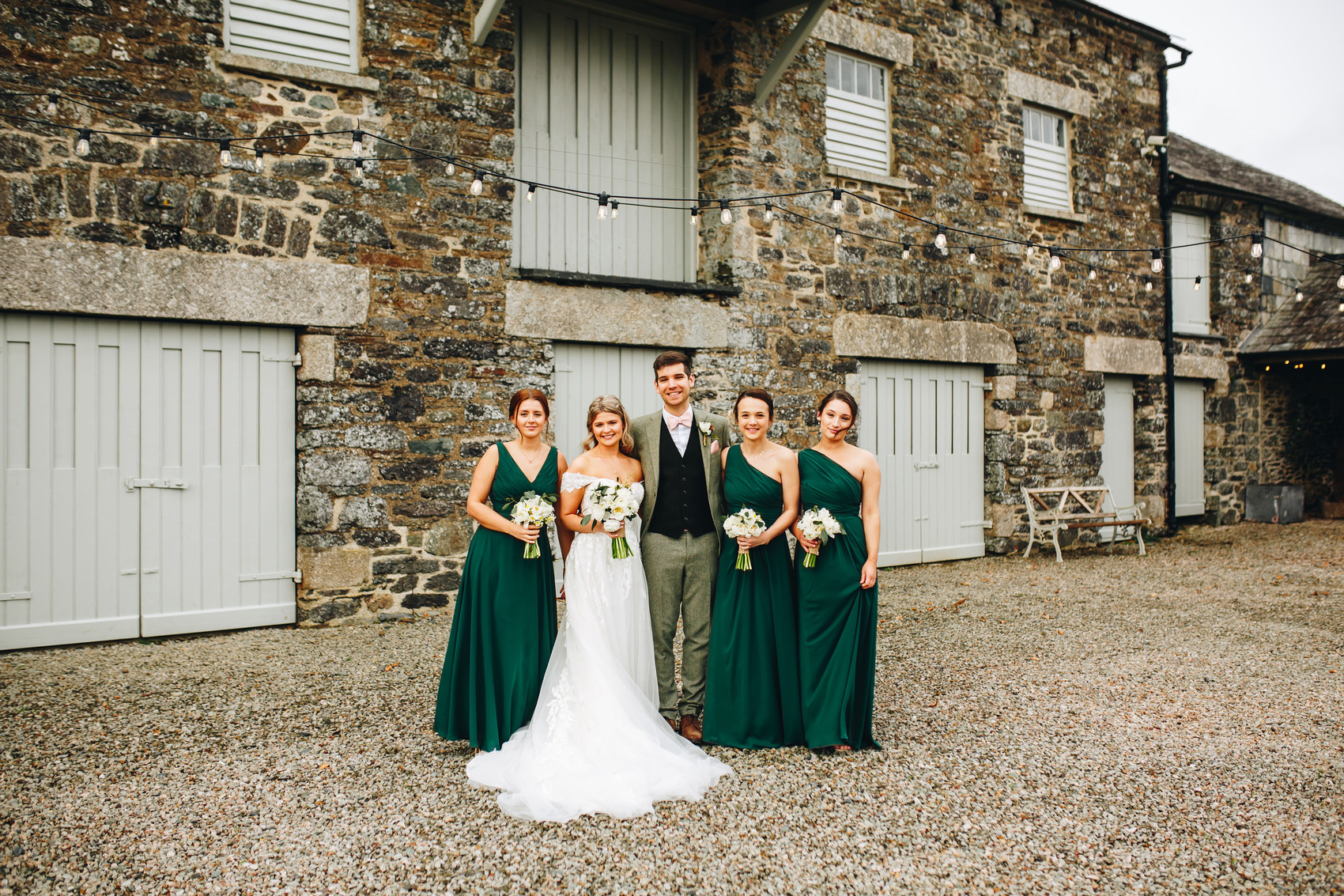 Bride, groom and bridesmaids in front of a barn