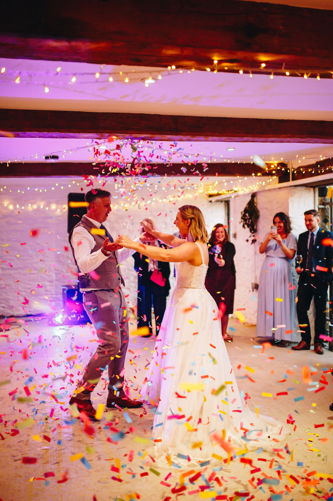 Confetti-filled first dance in a low ceilinged barn room