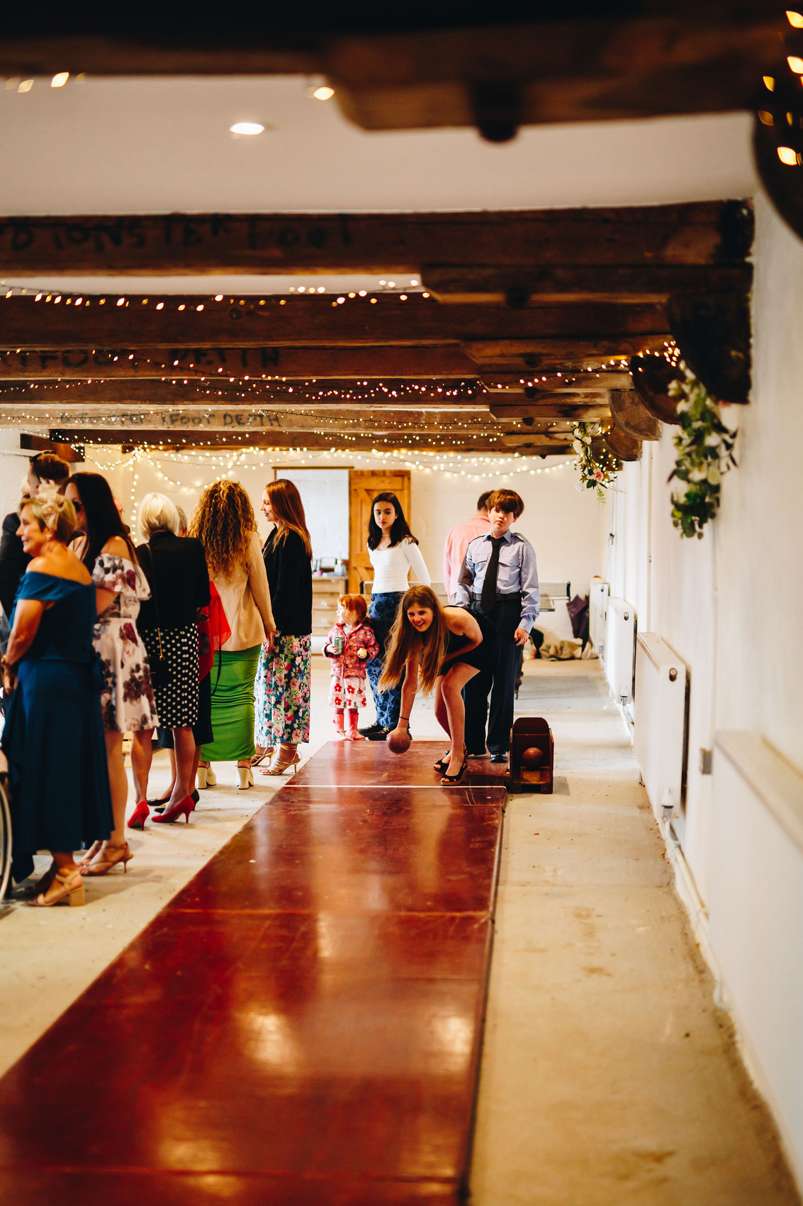 Wedding guests bowling in barn room