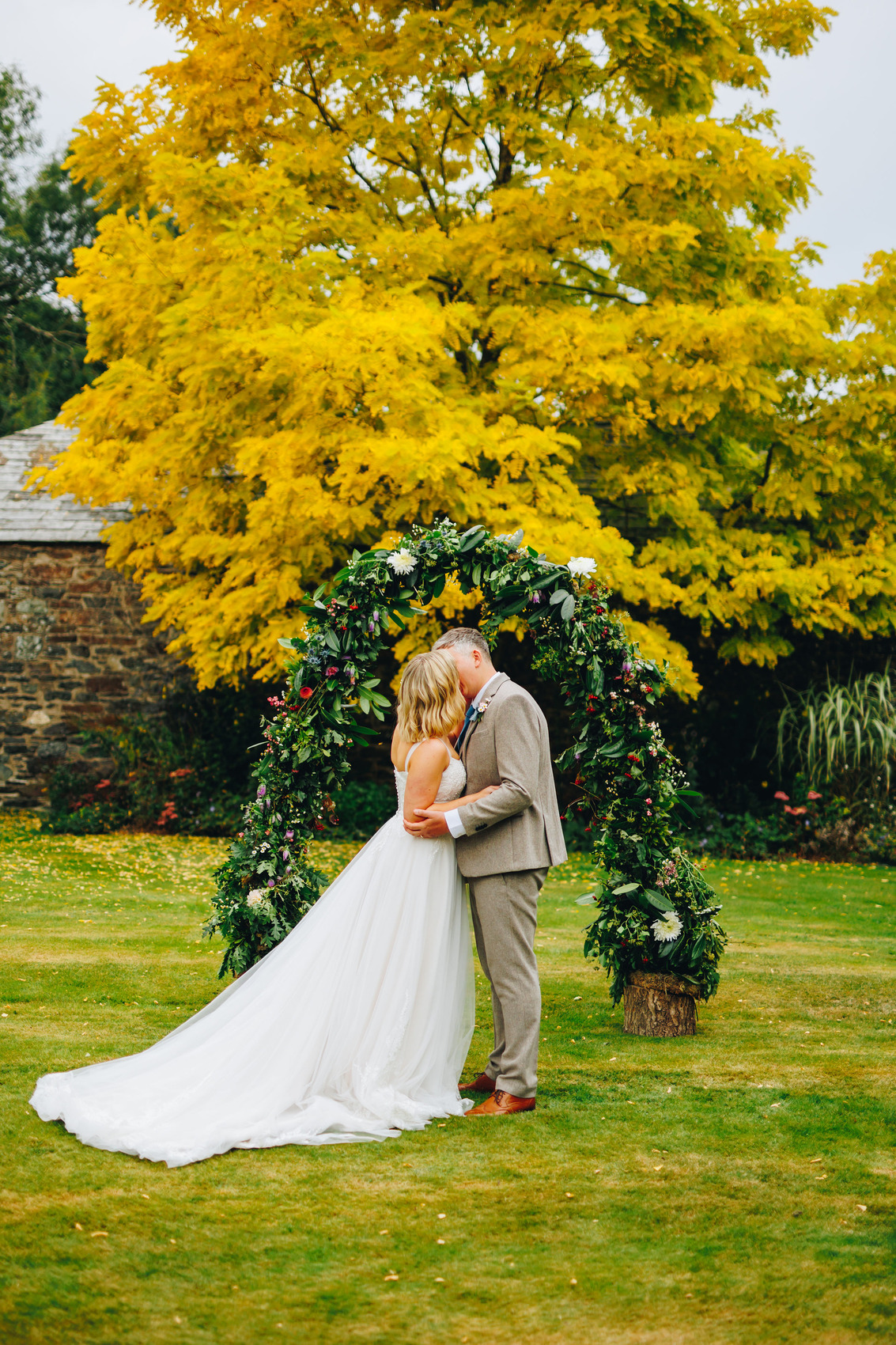 Couple at top of aisle outside with flower arch