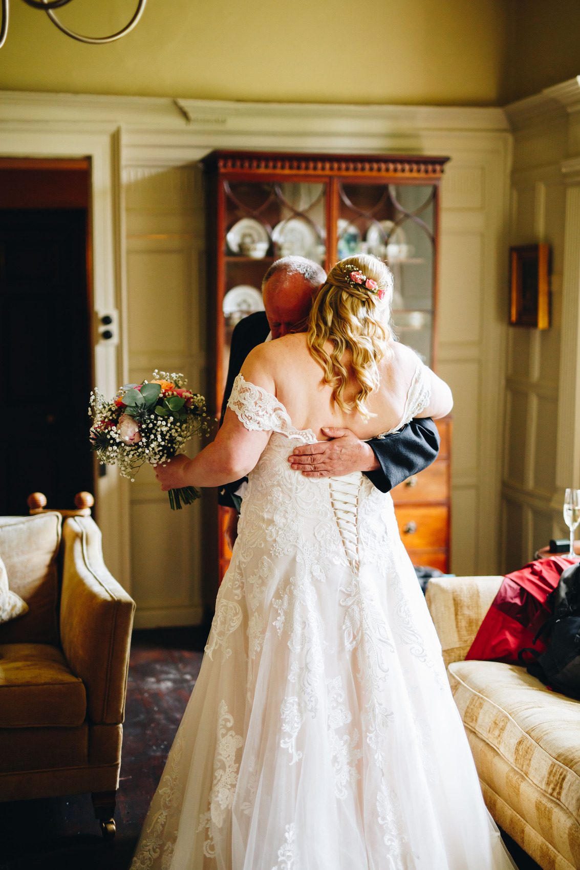 Bride hugging dad before wedding, holding flowers