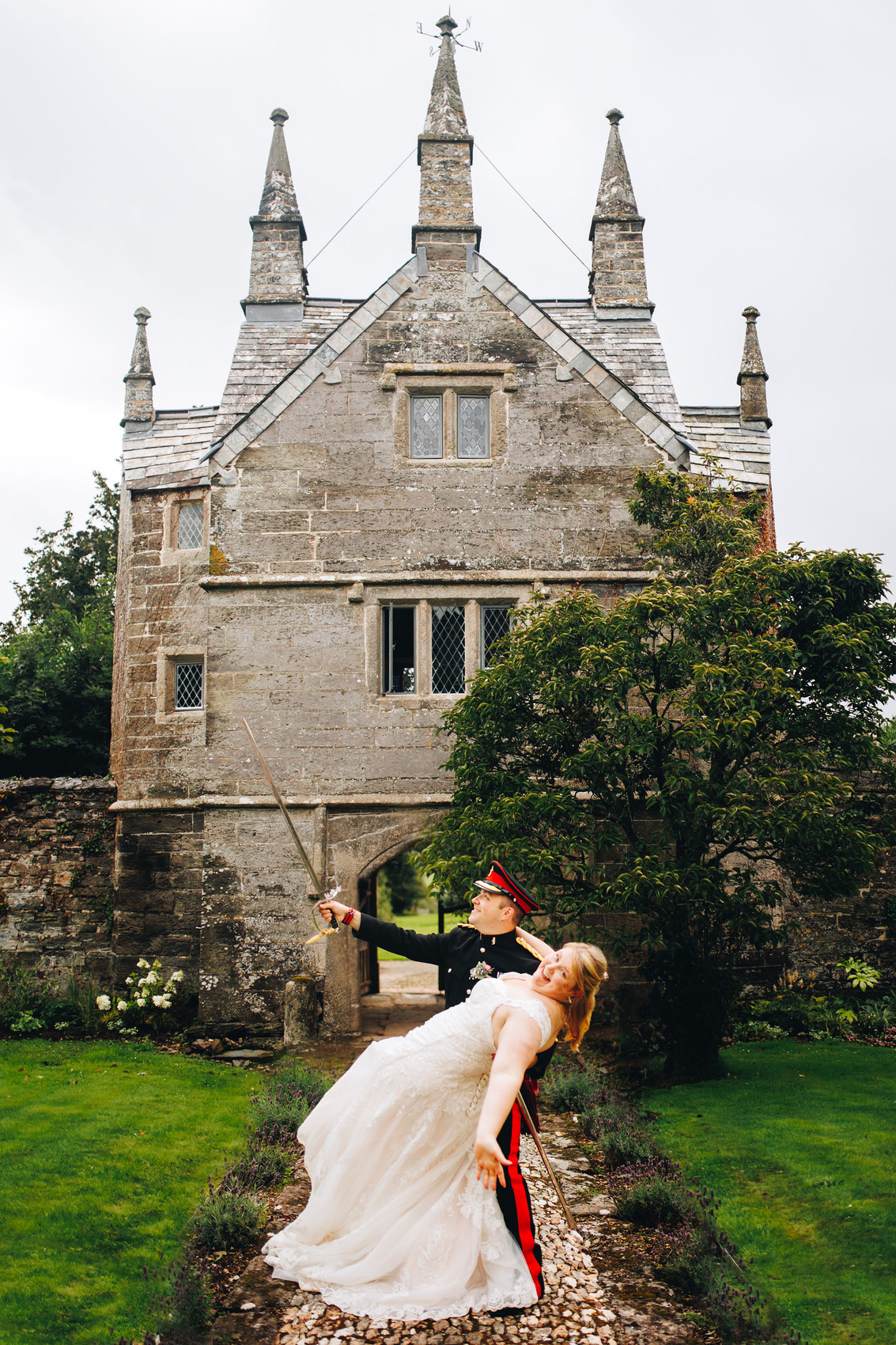 Couple looking happy in front of a gatehouse building