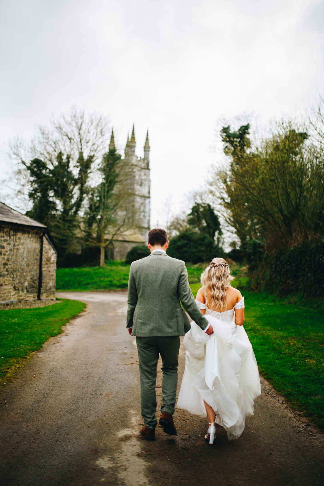 Wedding day couple walking away down the track