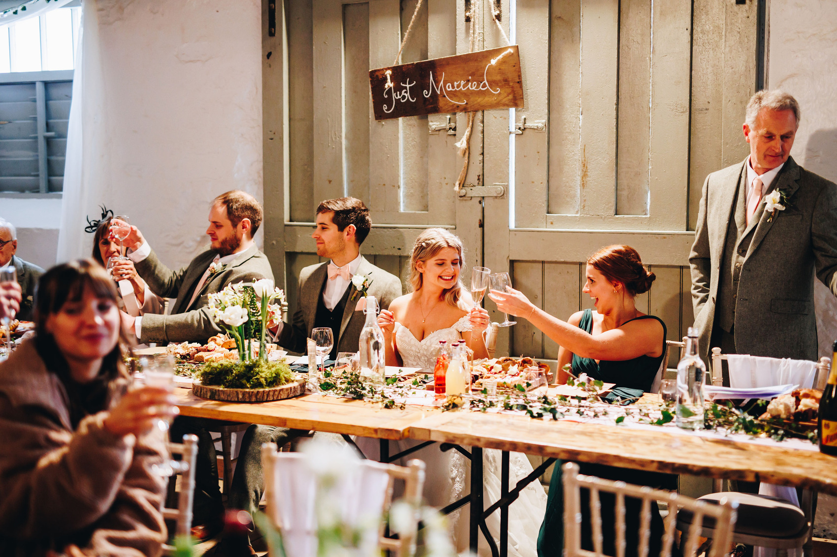Bride clinks champagne glass with bridesmaid at top table