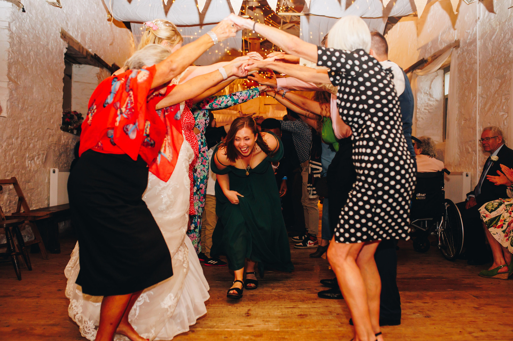 Bridesmaid running through people with arms raised at wedding reception party