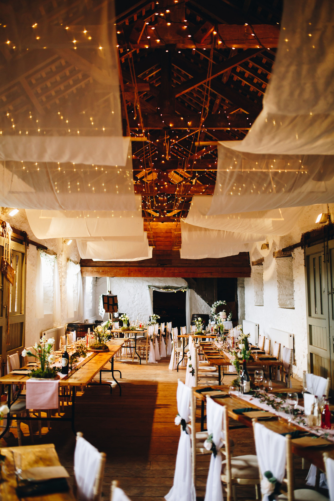 Long barn room with tables set up for a wedding reception