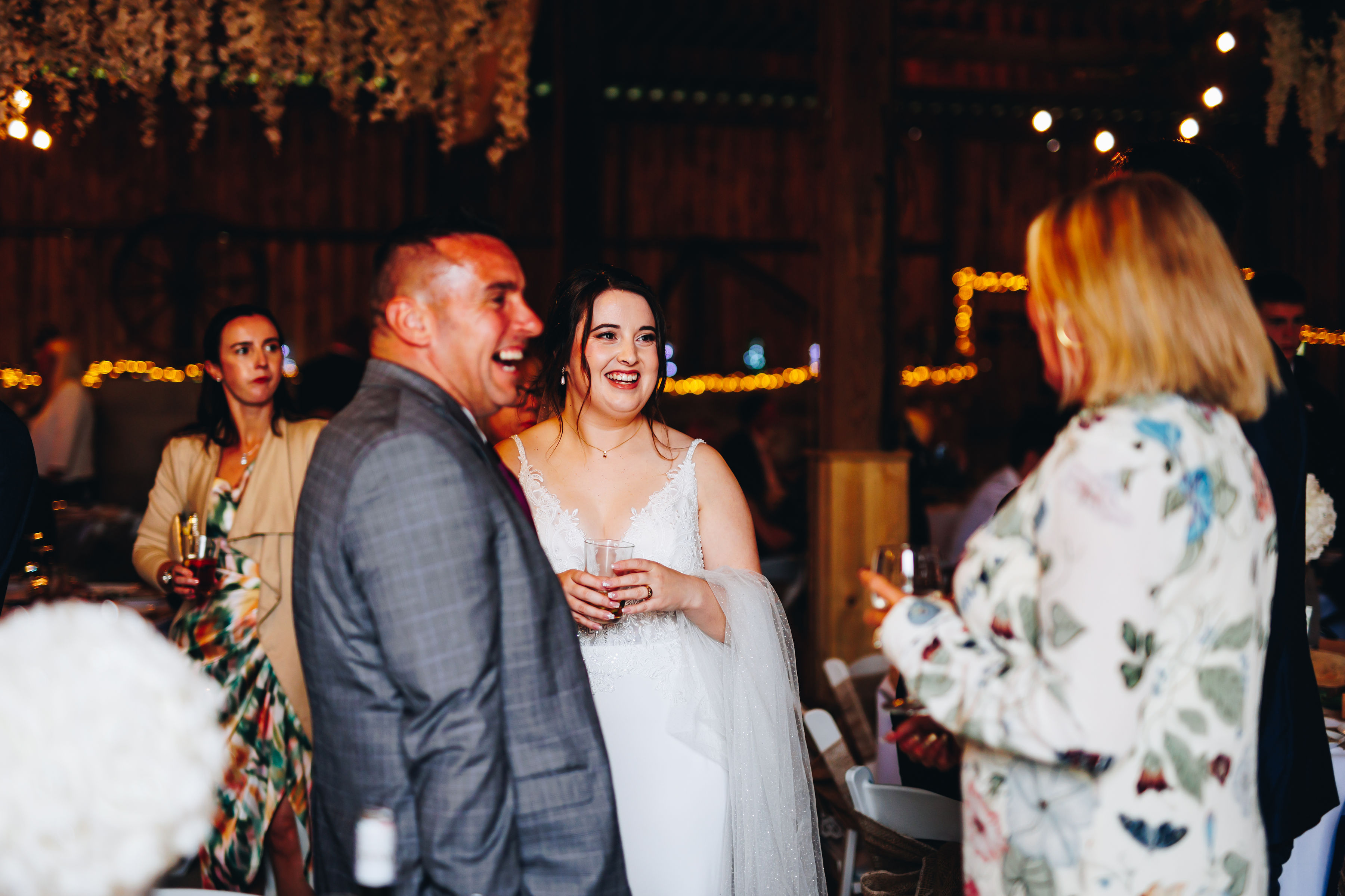 Bride smiling with family in dark barn
